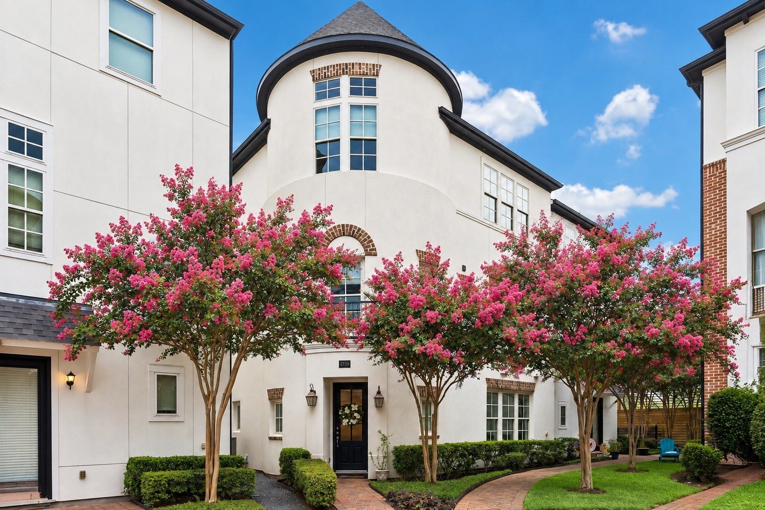 2725 Cohn Garden, Houston, TX 77007 Classic architecture meets a lush courtyard setting, where vibrant crepe myrtles frame the distinctive stucco faade and turret inspired roofline.