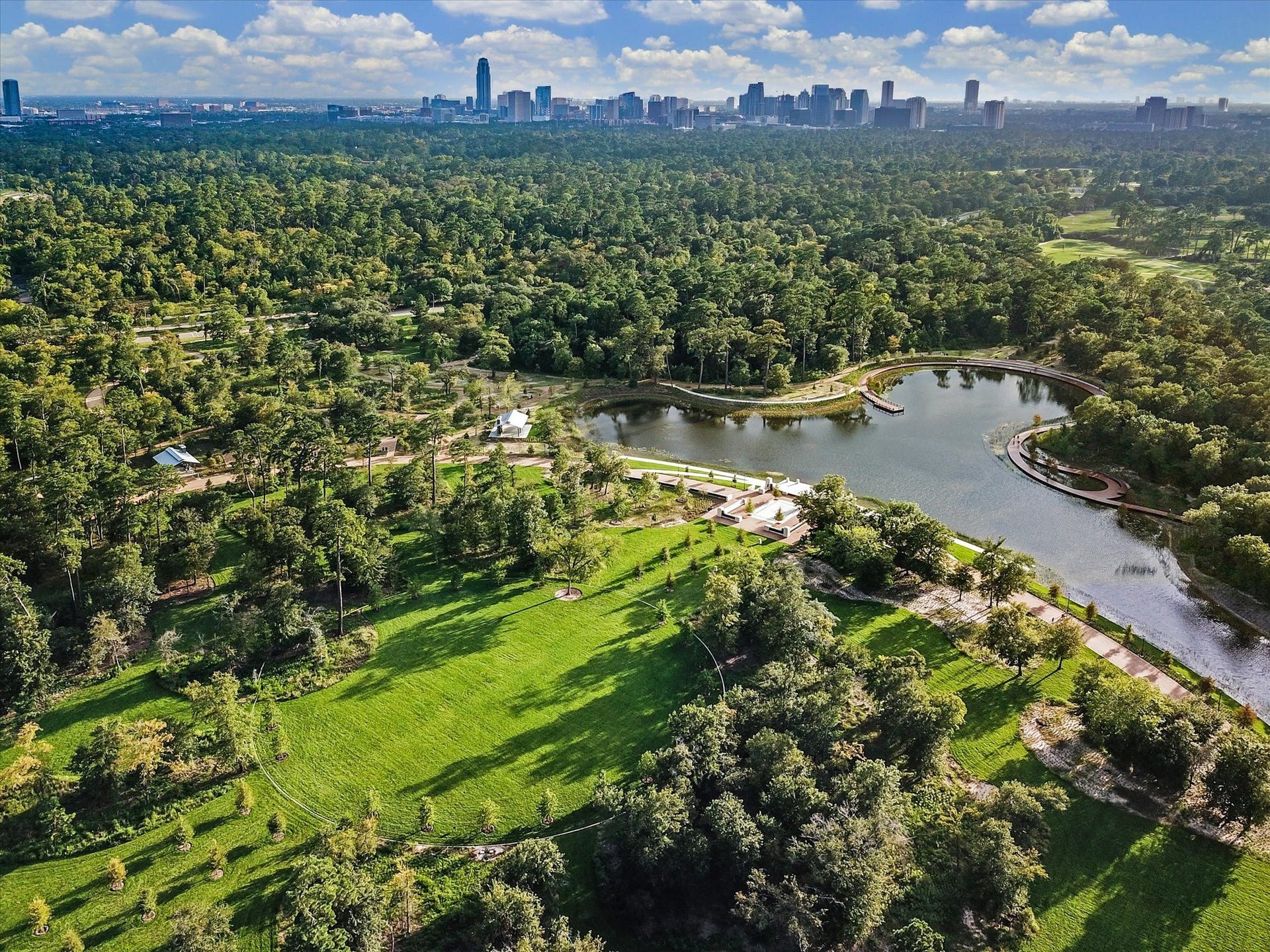 2725 Cohn Garden, Houston, TX 77007 Aerial view of Memorial Park showcasing the iconic Land Bridge, expansive green space, and miles of hike and bike trails, with the Houston skyline visible in the distance.
