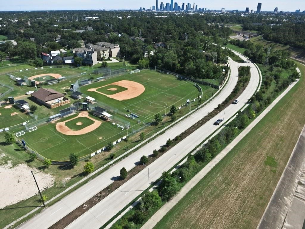 2725 Cohn Garden, Houston, TX 77007 Aerial view of Heights Hike & Bike Trail running alongside neighborhood athletic fields, offering direct access to outdoor recreation with downtown Houston visible in the distance.