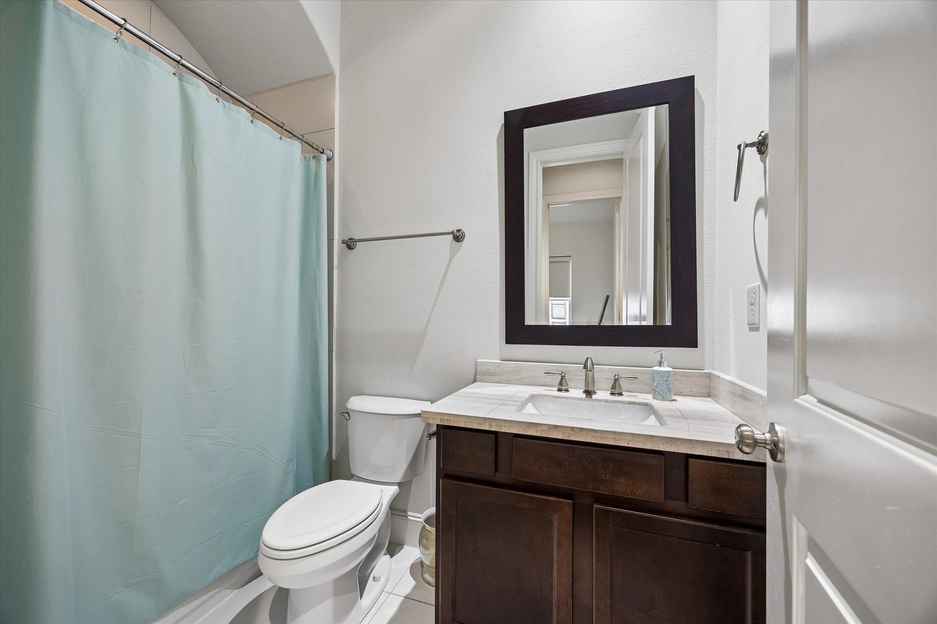 2725 Cohn Garden, Houston, TX 77007 Well appointed secondary bath features a stone topped vanity, dark wood cabinetry, and a tub and shower combination, offering a private and comfortable setup for guests or family.