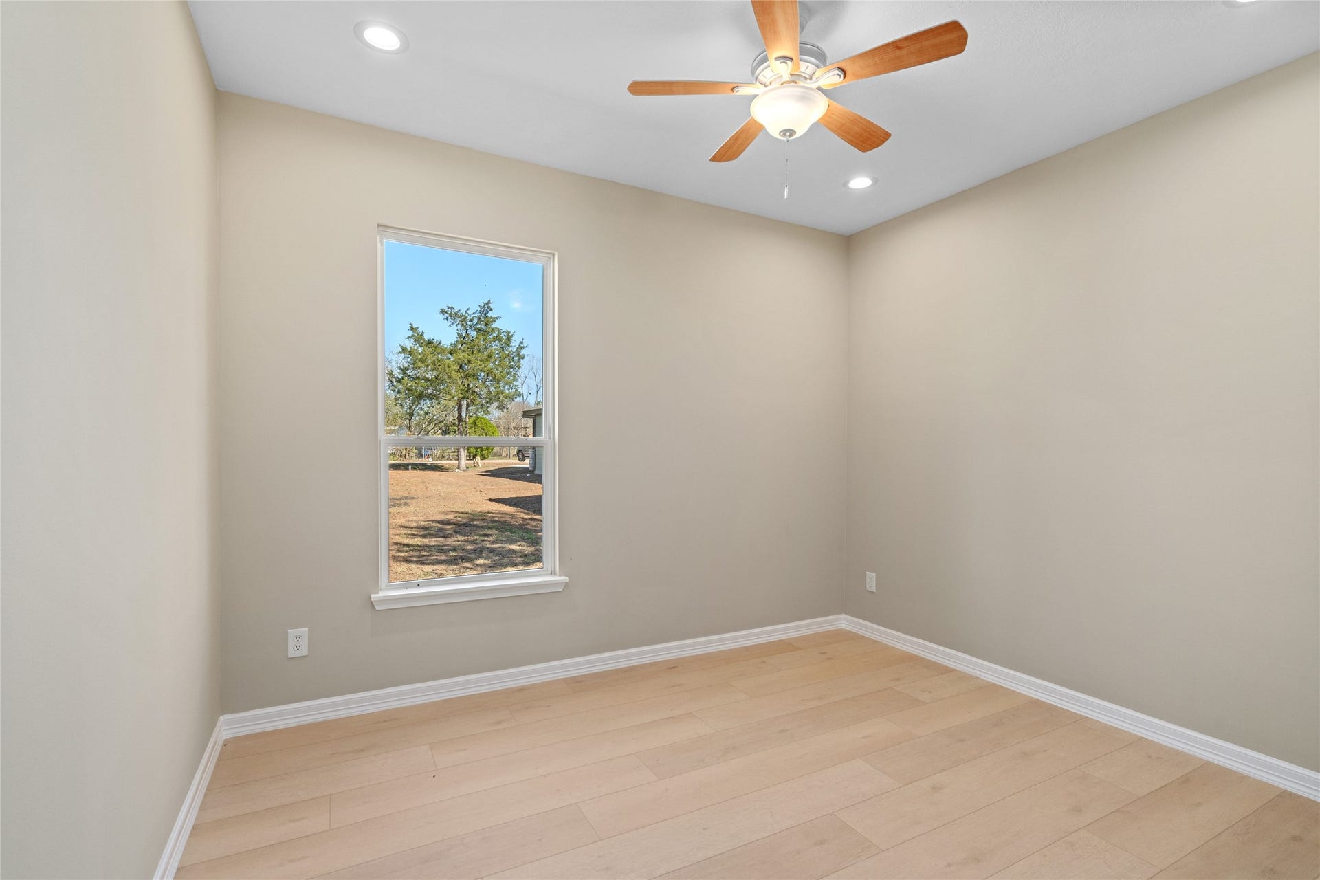 Cozy bedroom bathed in natural light with soft neutral walls and hardwood floorsready for your personal touch.