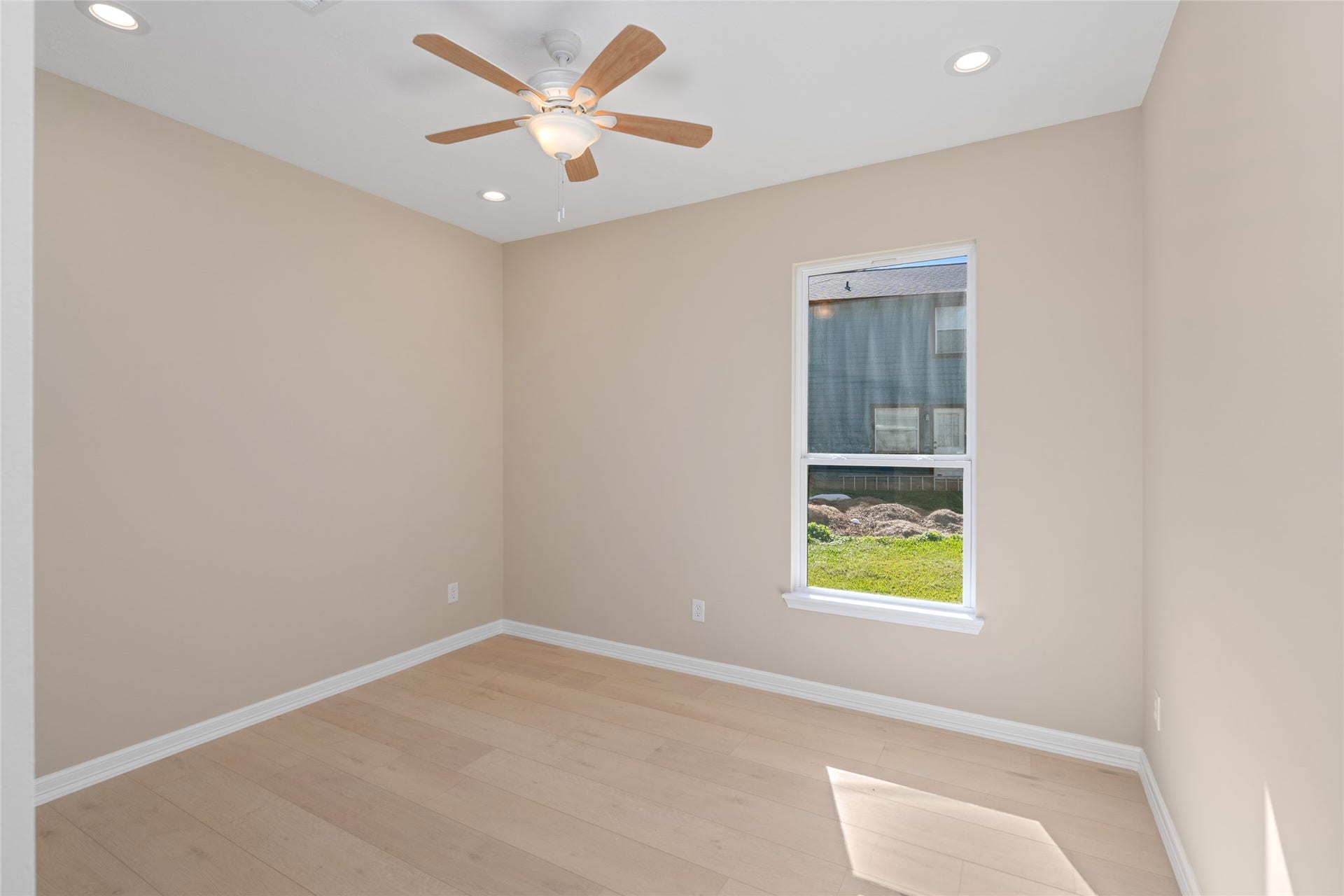 Bright secondary bedroom with large window and ceiling fan. Comfort, light, and style combine effortlessly.