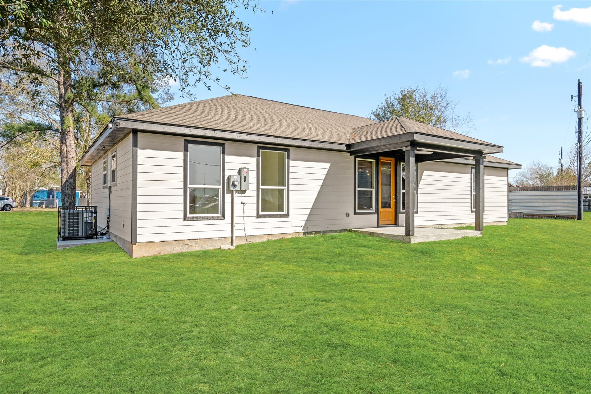 Another angle of the backyard highlighting the open green space and charming modern exterior.