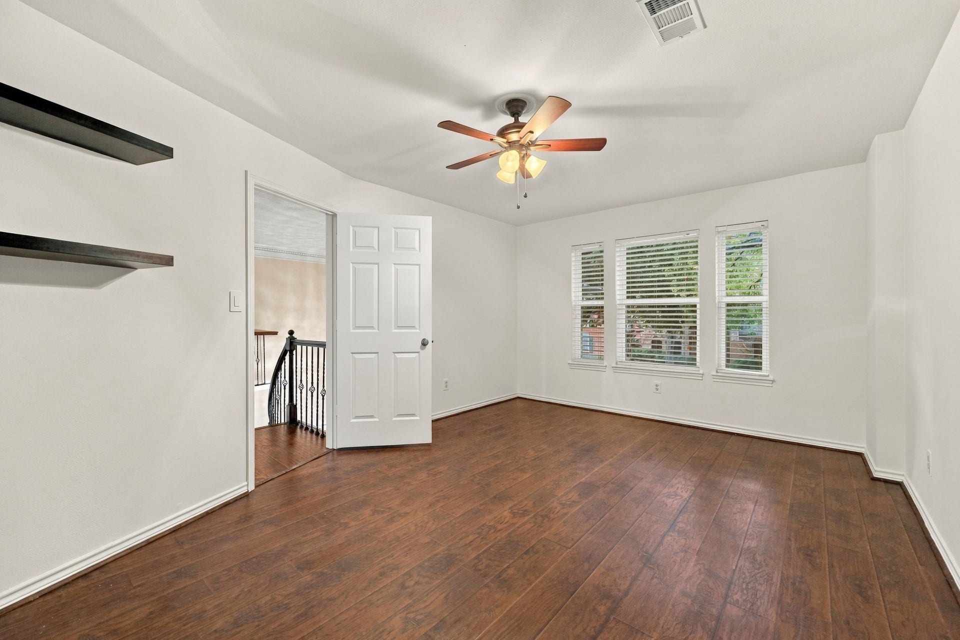 1430 Stependale Drive, Katy, TX 77450 Spacious bedroom with wood-look flooring, ceiling fan, built-in shelving, and multiple windows providing natural light.