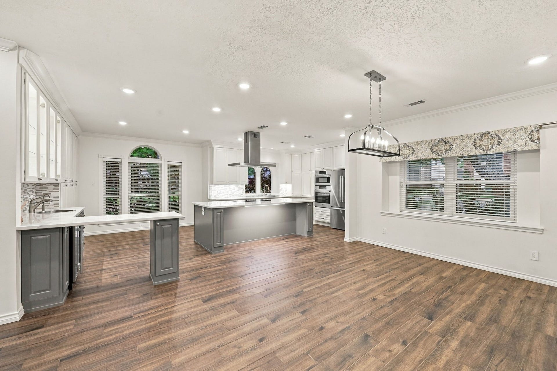 1430 Stependale Drive, Katy, TX 77450 Open-concept kitchen and dining space featuring white cabinetry, a gray island, modern finishes, and wood-look flooring.