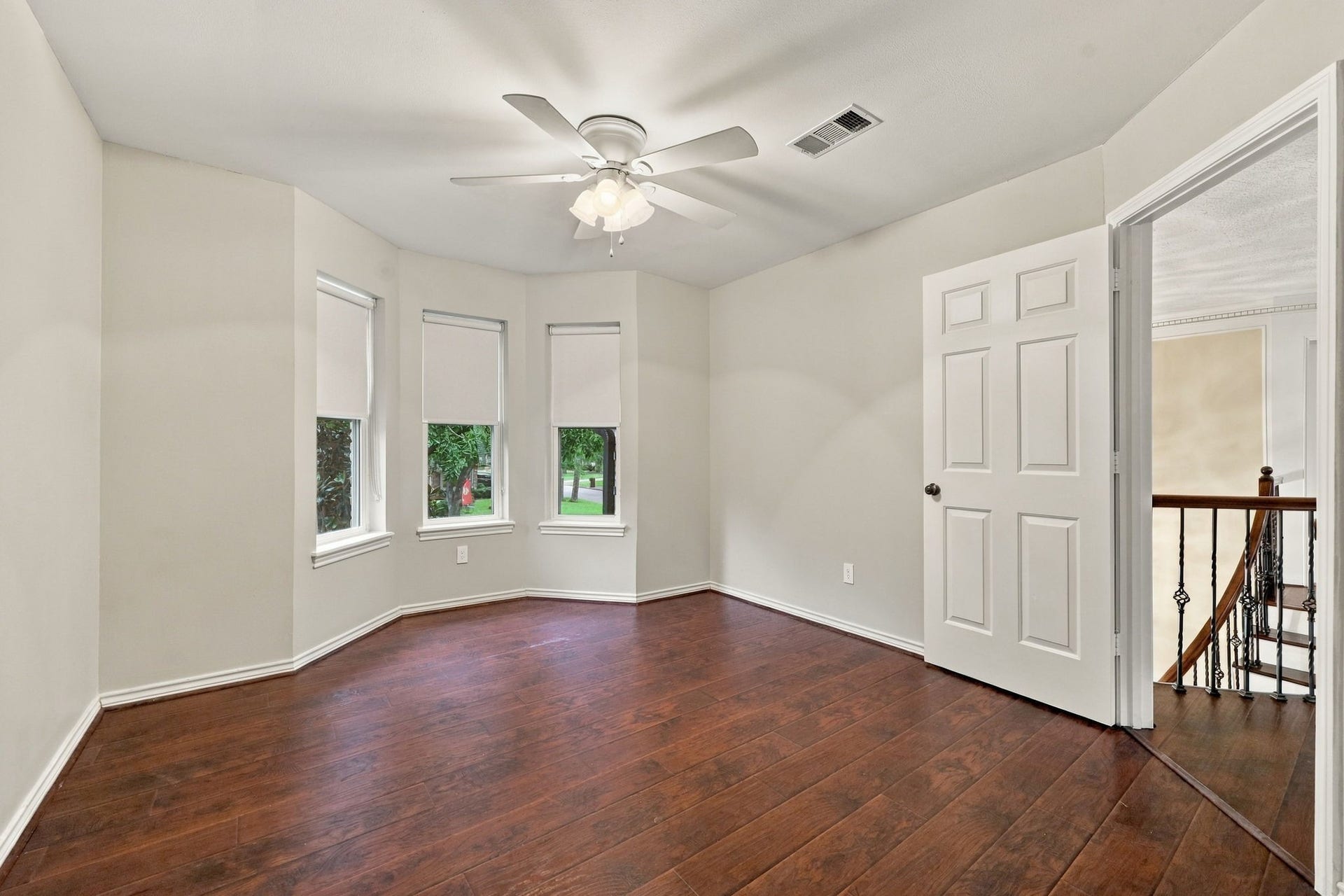 1430 Stependale Drive, Katy, TX 77450 Bright bedroom featuring wood-look flooring, multiple windows, a ceiling fan, and access to the upper-level landing.