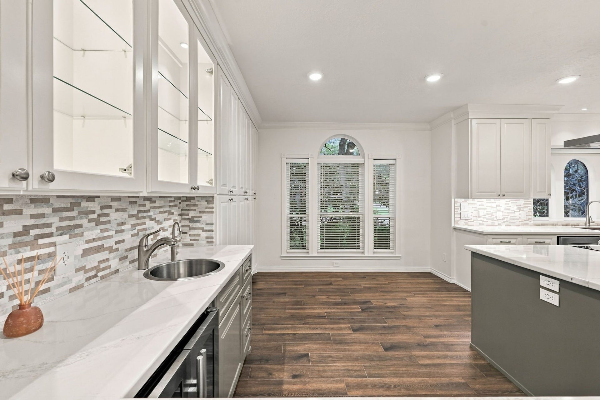 1430 Stependale Drive, Katy, TX 77450 Kitchen sink positioned beneath elegant arched windows, complemented by white cabinetry and stone countertops.