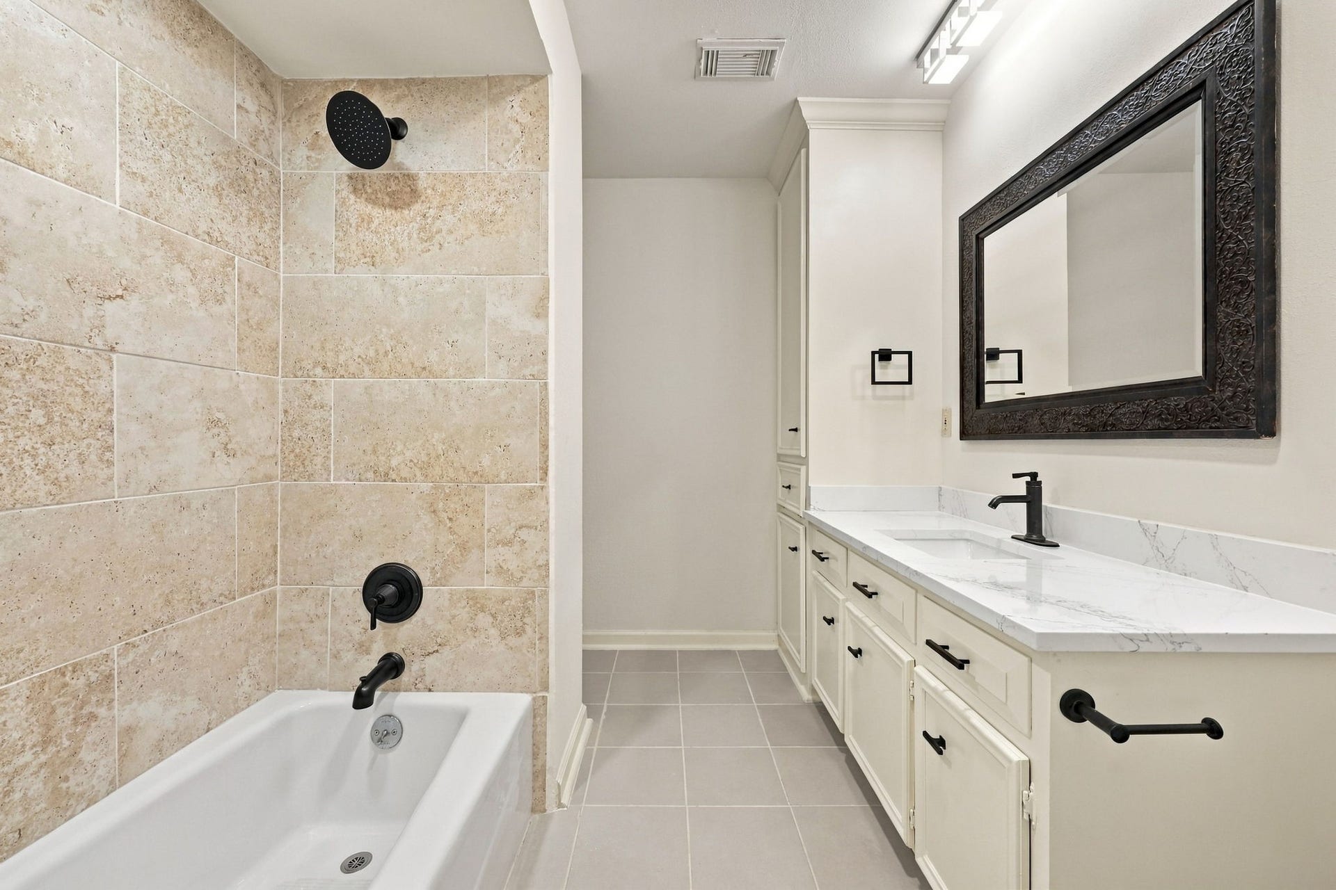 1430 Stependale Drive, Katy, TX 77450 Updated bathroom showcasing a long vanity with ample counter space, modern fixtures, and a tiled bathtub area.