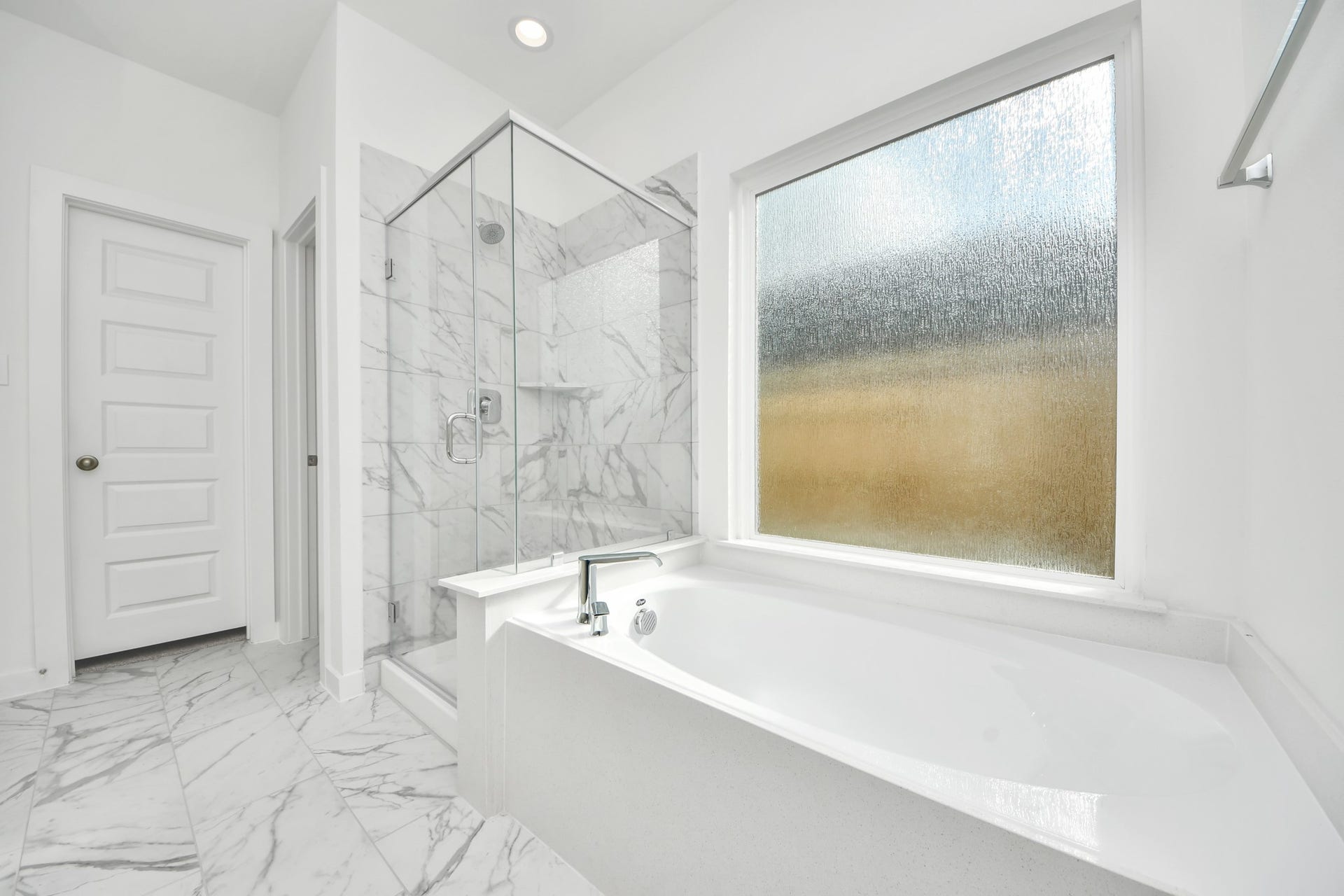 5822 Madison Trail Drive, Richmond, TX 77469 Escape to a spa-like oasis in this primary bathroom. Enjoy a walk-in shower with tile surround, a separate garden tub with custom detailing, and an elegant vanity featuring light countertops, modern hardware, and beautiful recessed lights. Experience luxury and relaxation in every detail. Sample photo of completed home with similar floor plan. Actual colors and selections may vary.