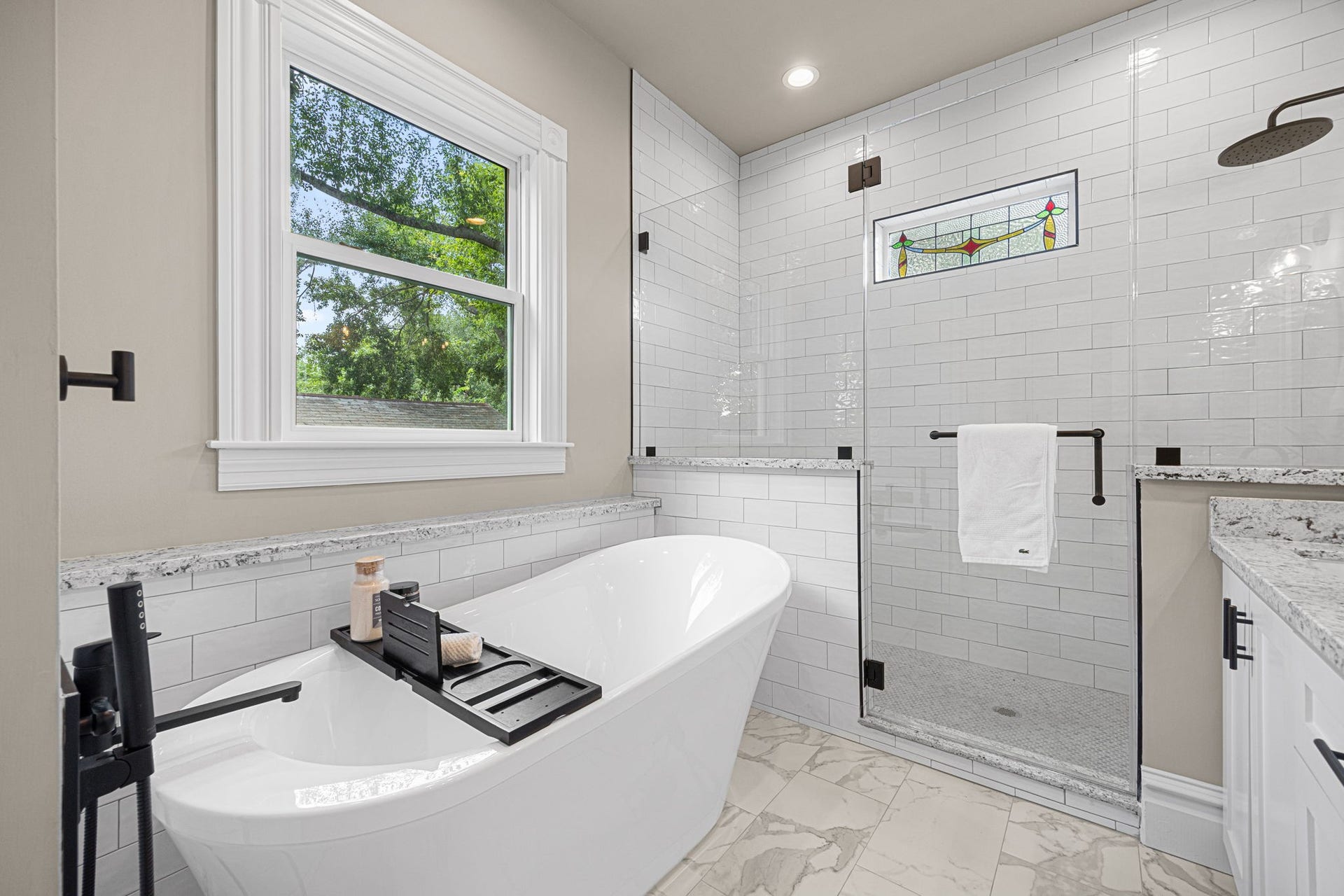 Oversized shower with frameless glass surround, and free-standing tub perfect for soaking.