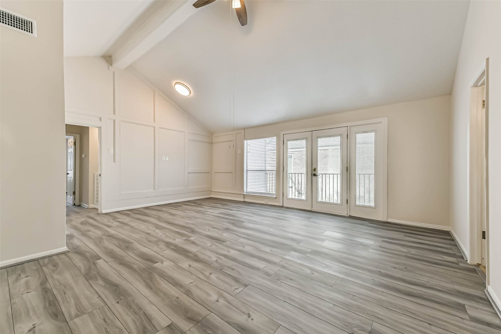 Another view of the primary shows the paneled walls and access to the private balcony.