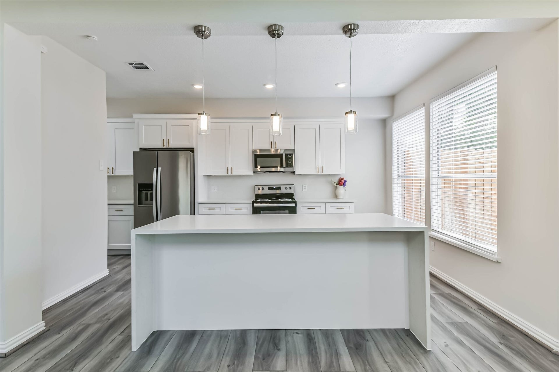 The kitchen features quartz counters, updated shaker style cabinetry with gold fixtures, stainless steel appliances and LED recessed lighting.