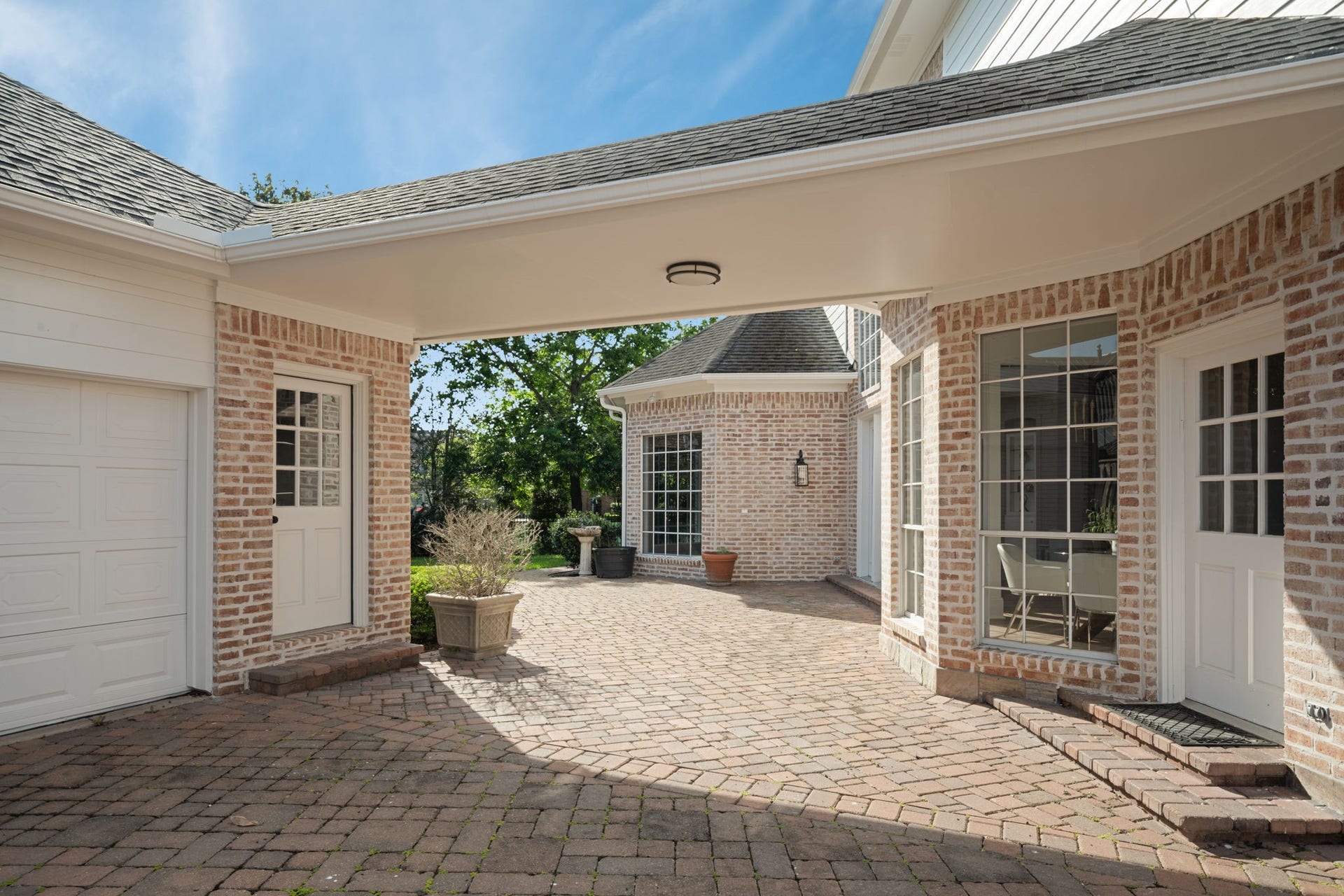 Just outside the breakfast area, the brick paver patio areas create multiple outdoor spaces for entertaining, dining, or everyday use. Multiple exterior access points connect the interior living areas to the backyard and surrounding courtyard spaces. Mature landscaping enhances privacy throughout the outdoor setting.