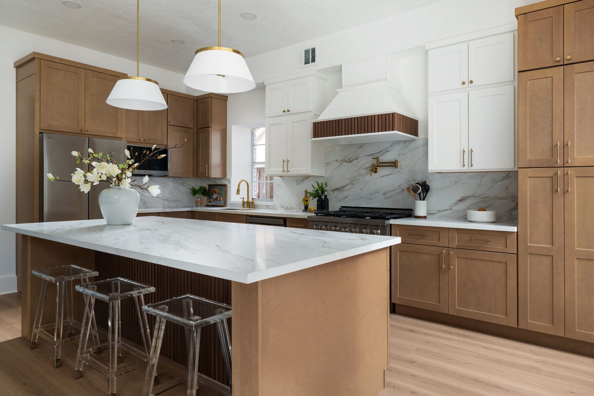 The kitchen was designed for both daily use and entertaining, featuring a gas cooktop, custom vent hood, and extensive cabinetry throughout. Quartz countertops and updated finishes create a clean, modern presentation. Wide openings maintain strong connection to the homes dining and living spaces.