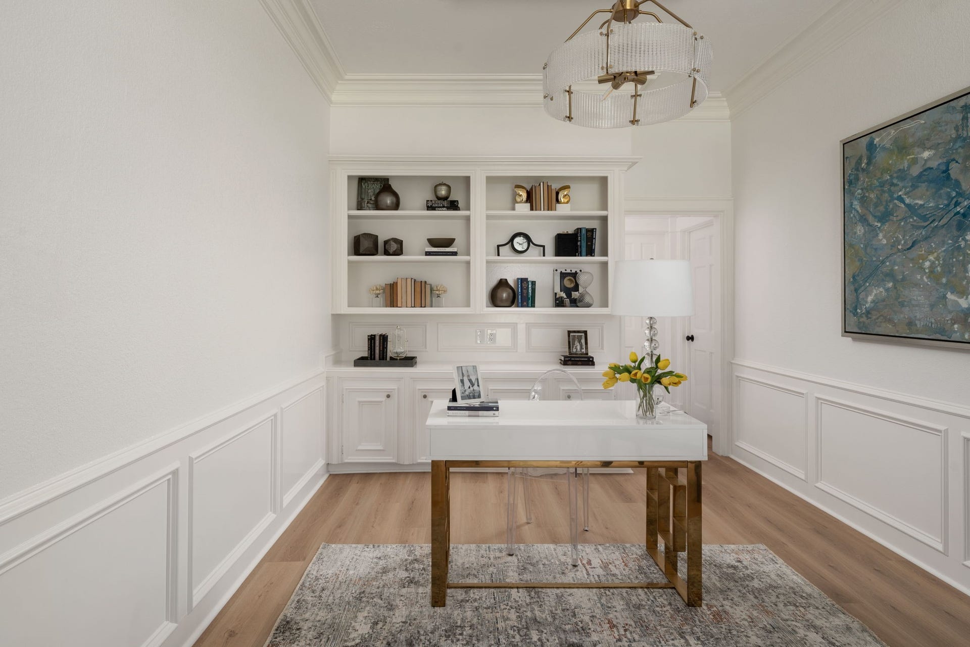 The private office overlooks the front entry and features custom built-in shelving, updated trim work, and recessed lighting throughout. A tray ceiling and contemporary chandelier add architectural detail to the space. Positioned near the foyer, the layout offers flexibility for work, reading, or additional living needs.