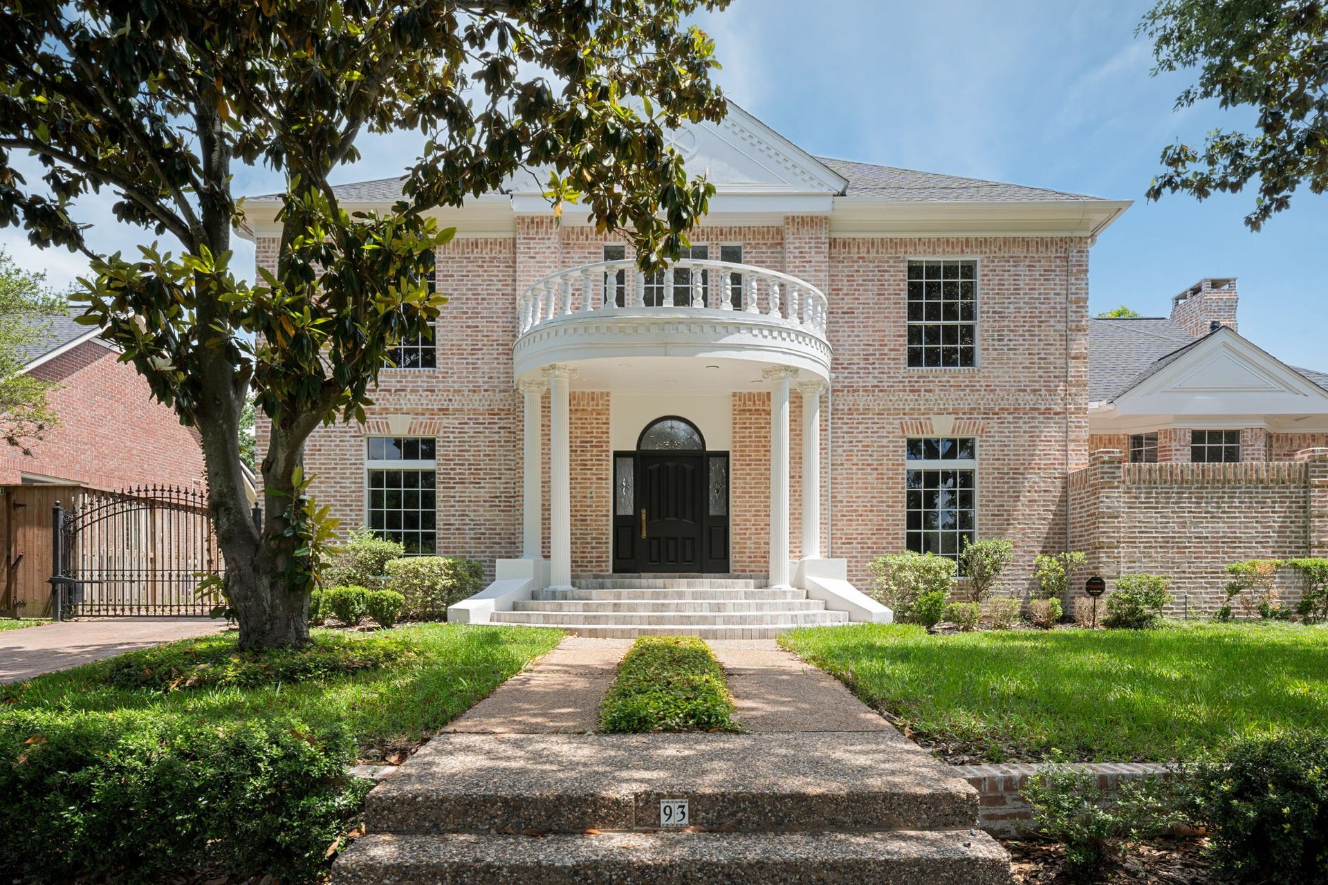 A long walkway leads to the two-story entry framed by columns, oversized windows, and German schmear brick detailing across the front elevation. The homes exterior architecture balances traditional design with a fully renovated presentation throughout the property. Positioned on a prominent corner lot within Sweetwater Section 1 in Sugar Land.