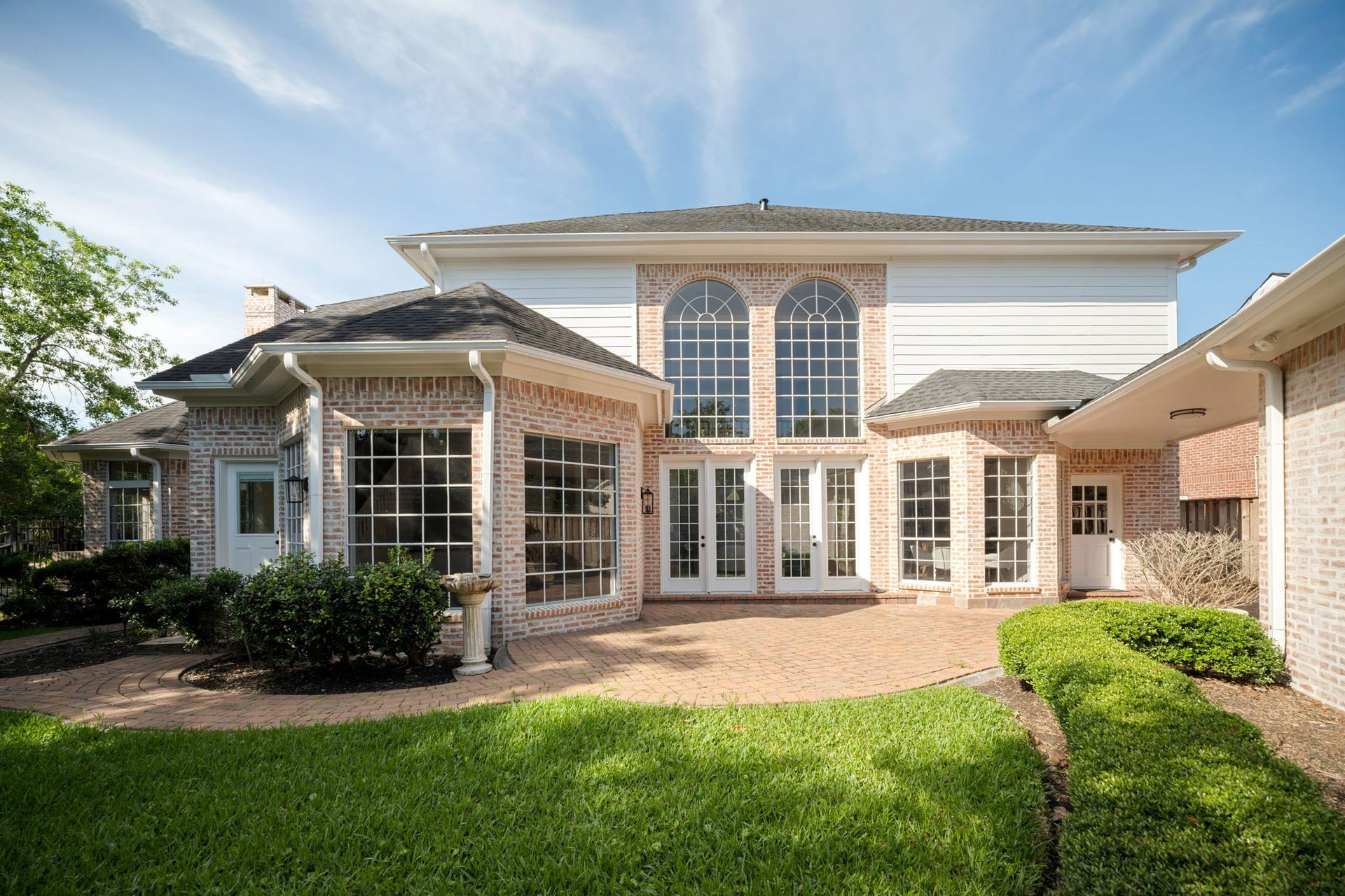 The backyard combines open green space with landscaped entertaining areas and mature trees surrounding the property. Large windows across the rear elevation bring natural light deep into the interior throughout the day. The roof was replaced within the last few years, complementing the homes extensive renovations and updates.