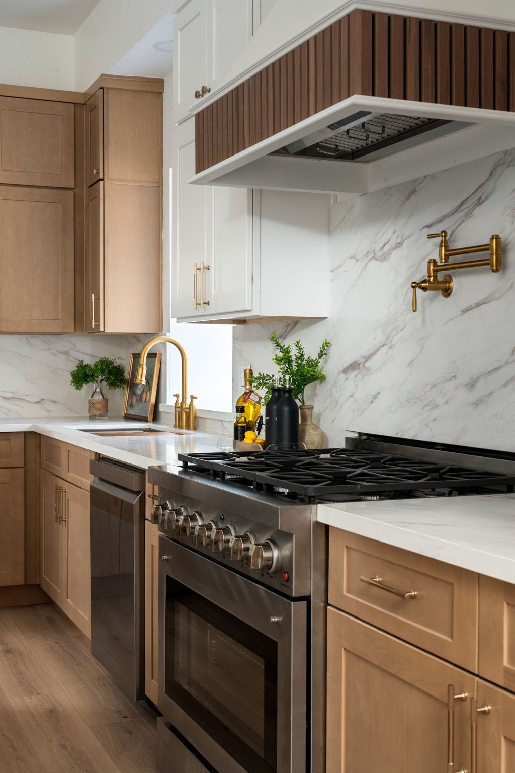 A gas cooktop, pot filler, and full-height backsplash create a functional focal point within the renovated kitchen. Extensive cabinetry and integrated storage enhance everyday usability while maintaining a clean visual design. Warm finishes and updated materials continue throughout the space.