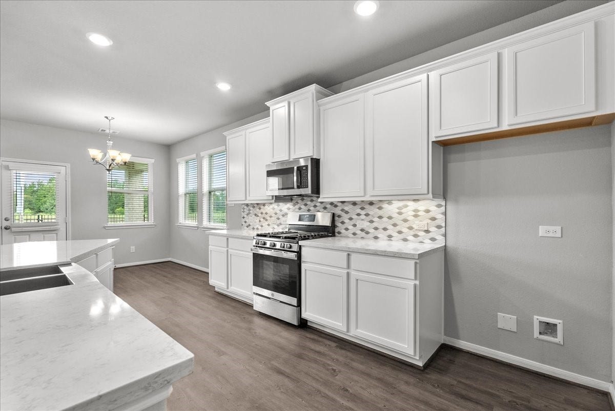 Chef's eat-in island kitchen features 42" cabinets with crown molding, stainless steel appliances and and designer backsplash