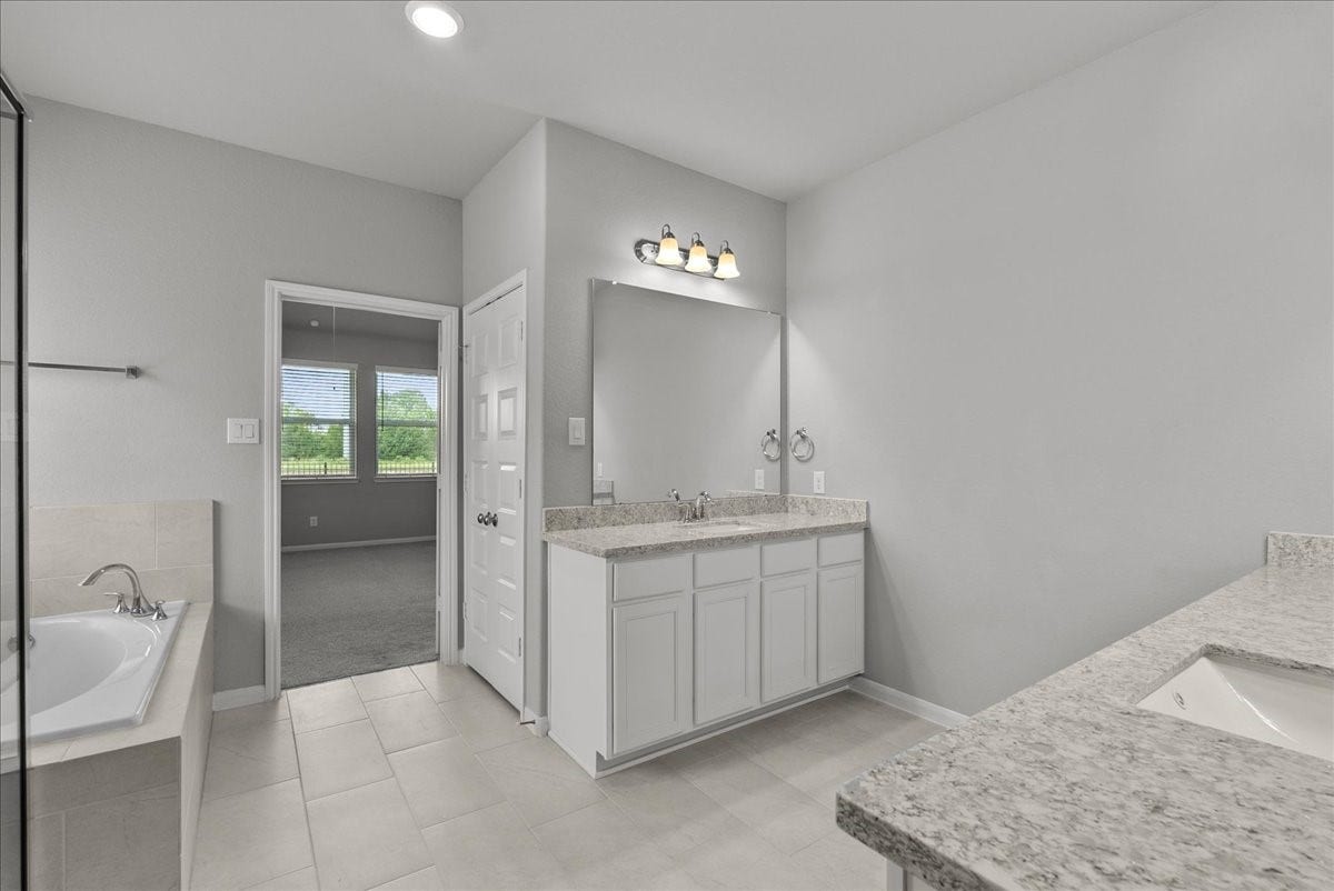 Primary bath features dual vanities, walk-in shower, soaking tub and a walk-in closet