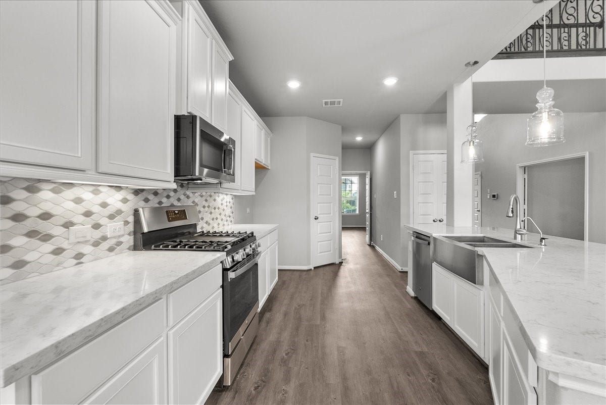 Chef's eat-in island kitchen features 42" cabinets with crown molding, stainless steel appliances and and designer backsplash