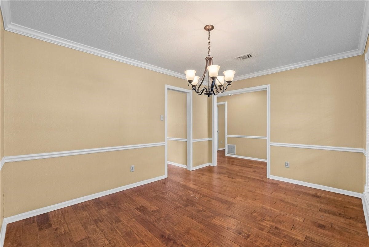 Elegant formal dining room featuring rich hardwood floors, crown molding, and a classic chandelier that sets the perfect ambiance for memorable gatherings.