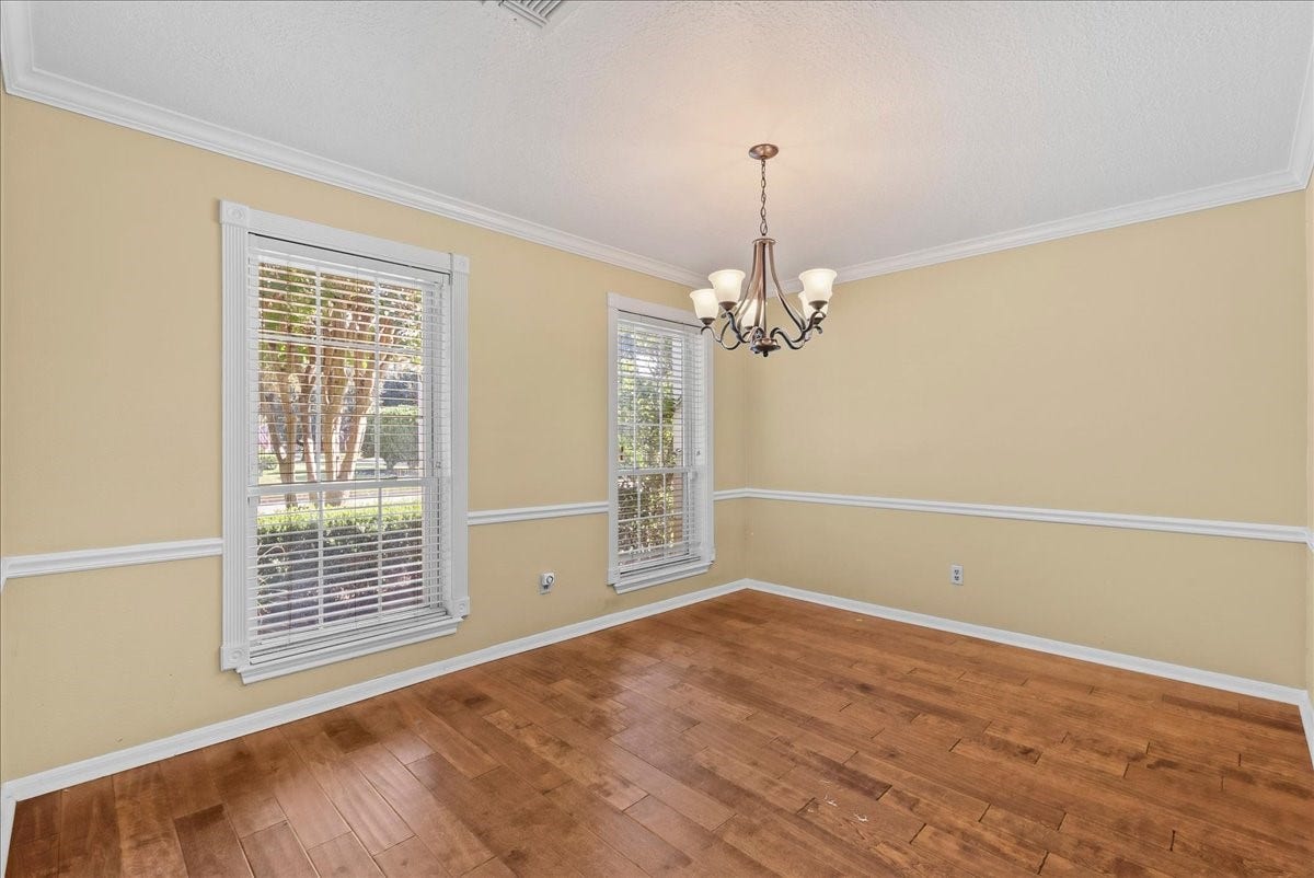Elegance meets charm in this formal dining room, featuring rich hardwood floors, ample natural light from large windows, and a classic chandelier for the perfect dining ambiance.