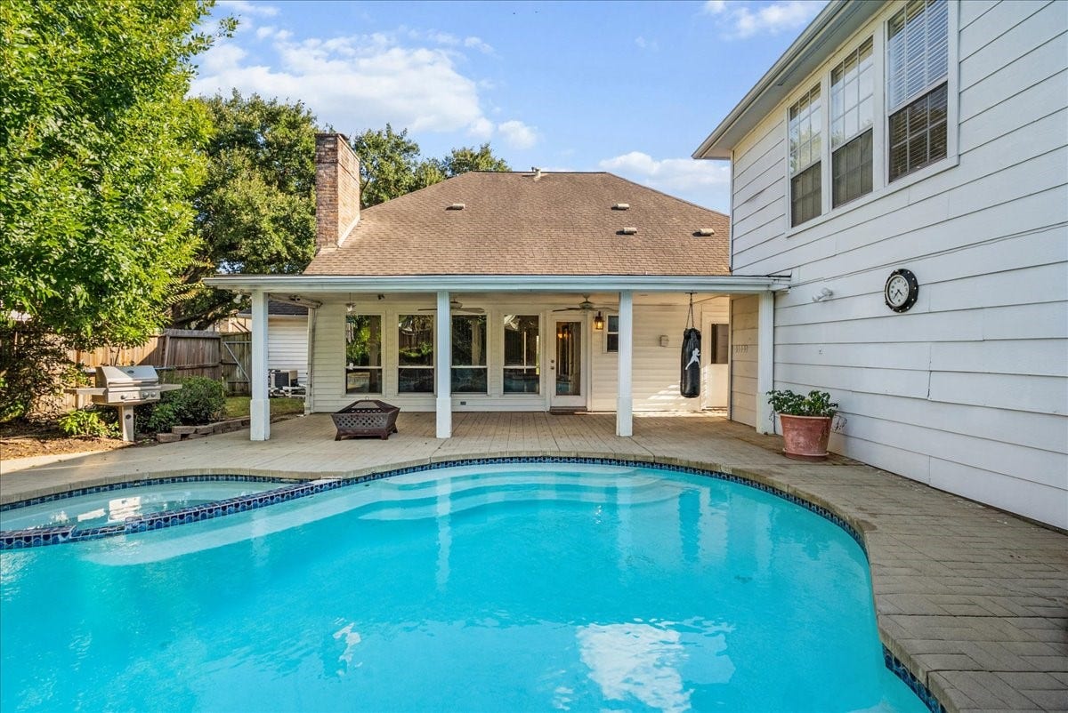 Spacious backyard oasis featuring a pristine swimming pool, covered patio, and ample room for outdoor entertaining.