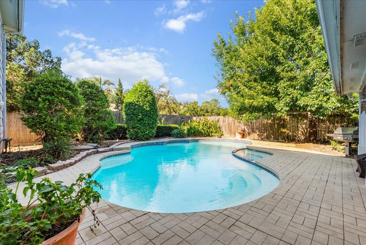 Experience serene outdoor living with a beautifully landscaped backyard featuring a sparkling pool and spacious patio, perfect for relaxation and entertainment.