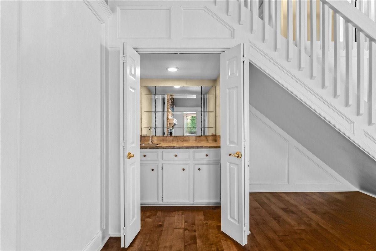 Discover the perfect spot for entertaining with a stylish wet bar tucked elegantly beneath the staircase, featuring ample cabinetry and a mirrored backsplash.