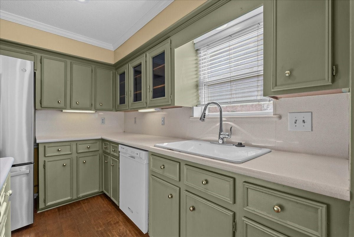 Charming kitchen with sage green cabinets, modern appliances, and ample natural light from a large window above the sink.