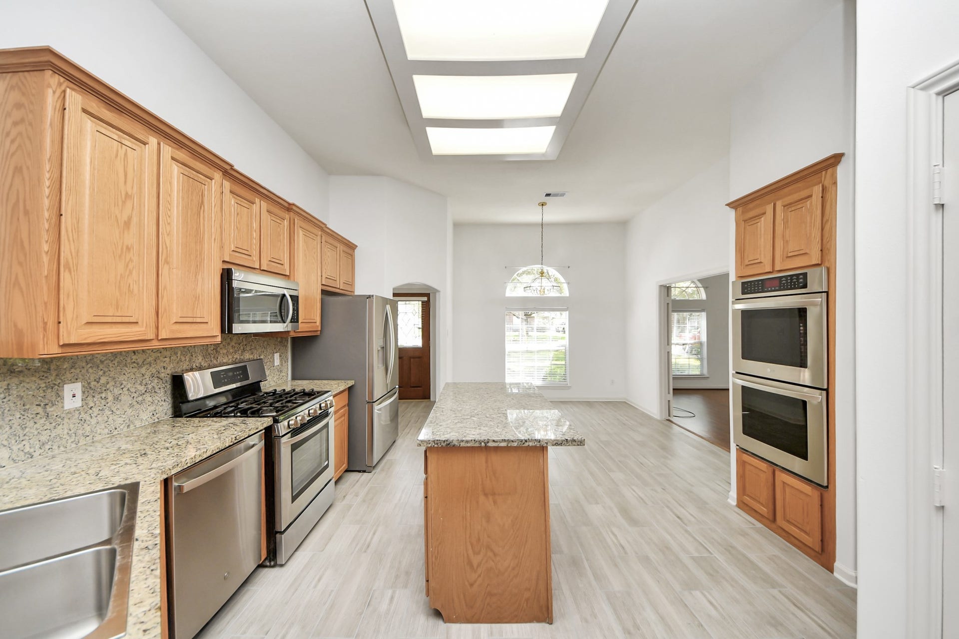 5815 Pheasant Ridge Lane, Houston, TX 77041 Spacious kitchen with granite countertops, modern stainless steel appliances, and abundant natural light, featuring a central island and warm wood cabinetry.