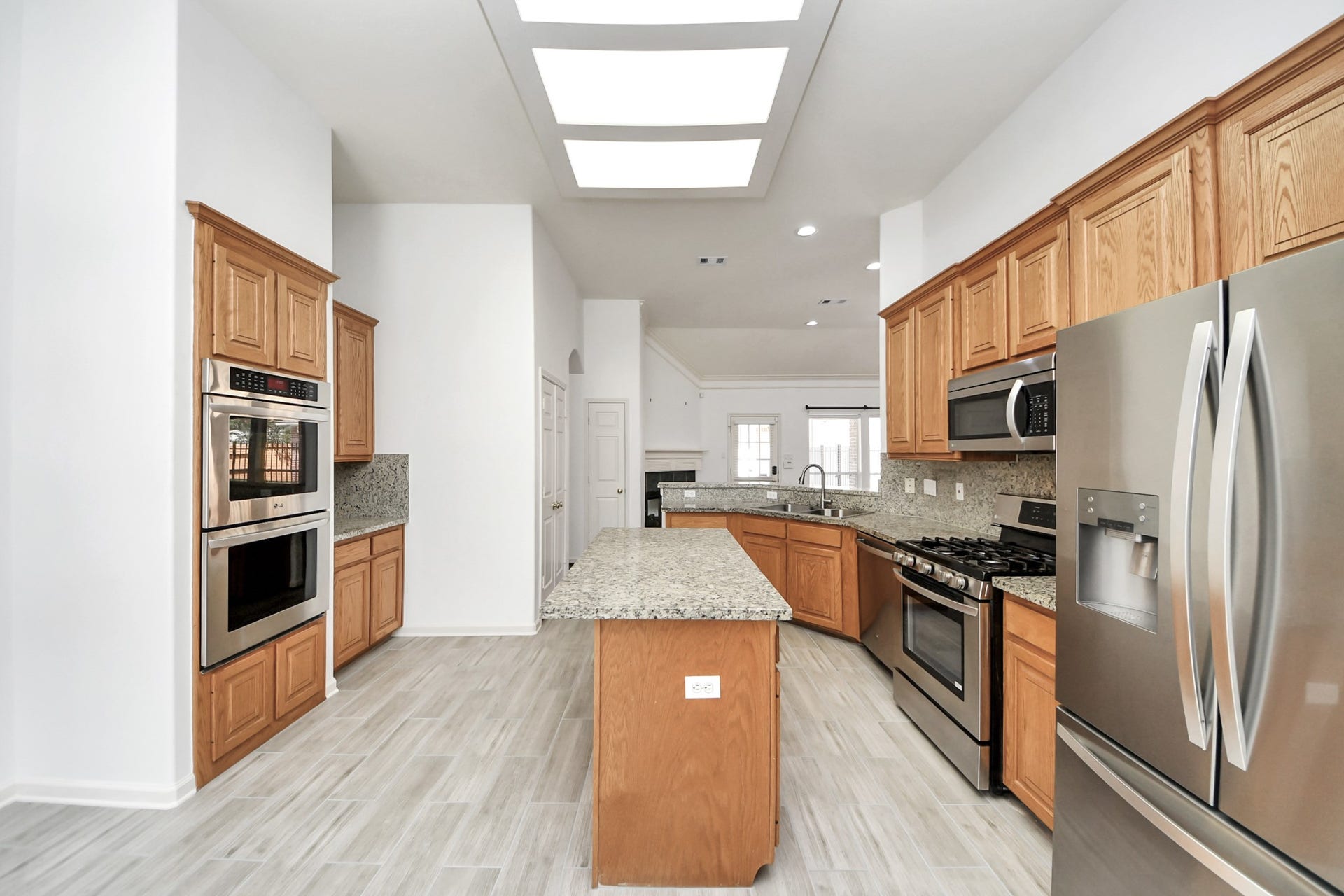 5815 Pheasant Ridge Lane, Houston, TX 77041 Spacious kitchen featuring granite countertops, stainless steel appliances, and ample wooden cabinetry, complemented by modern tile flooring and abundant natural light.