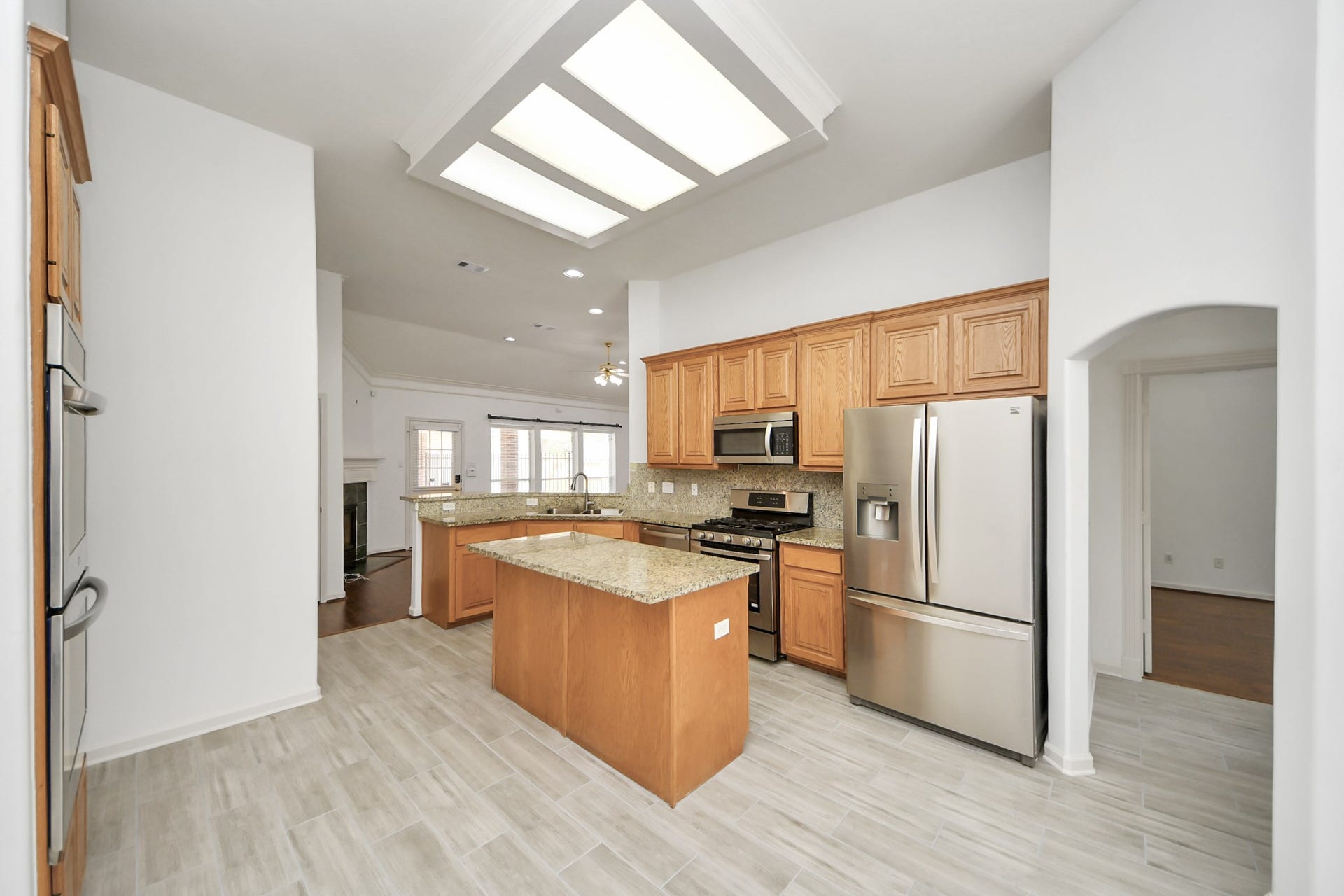 5815 Pheasant Ridge Lane, Houston, TX 77041 Spacious kitchen featuring modern stainless steel appliances, granite countertops, and ample wooden cabinetry, accented by elegant tile flooring and recessed lighting.