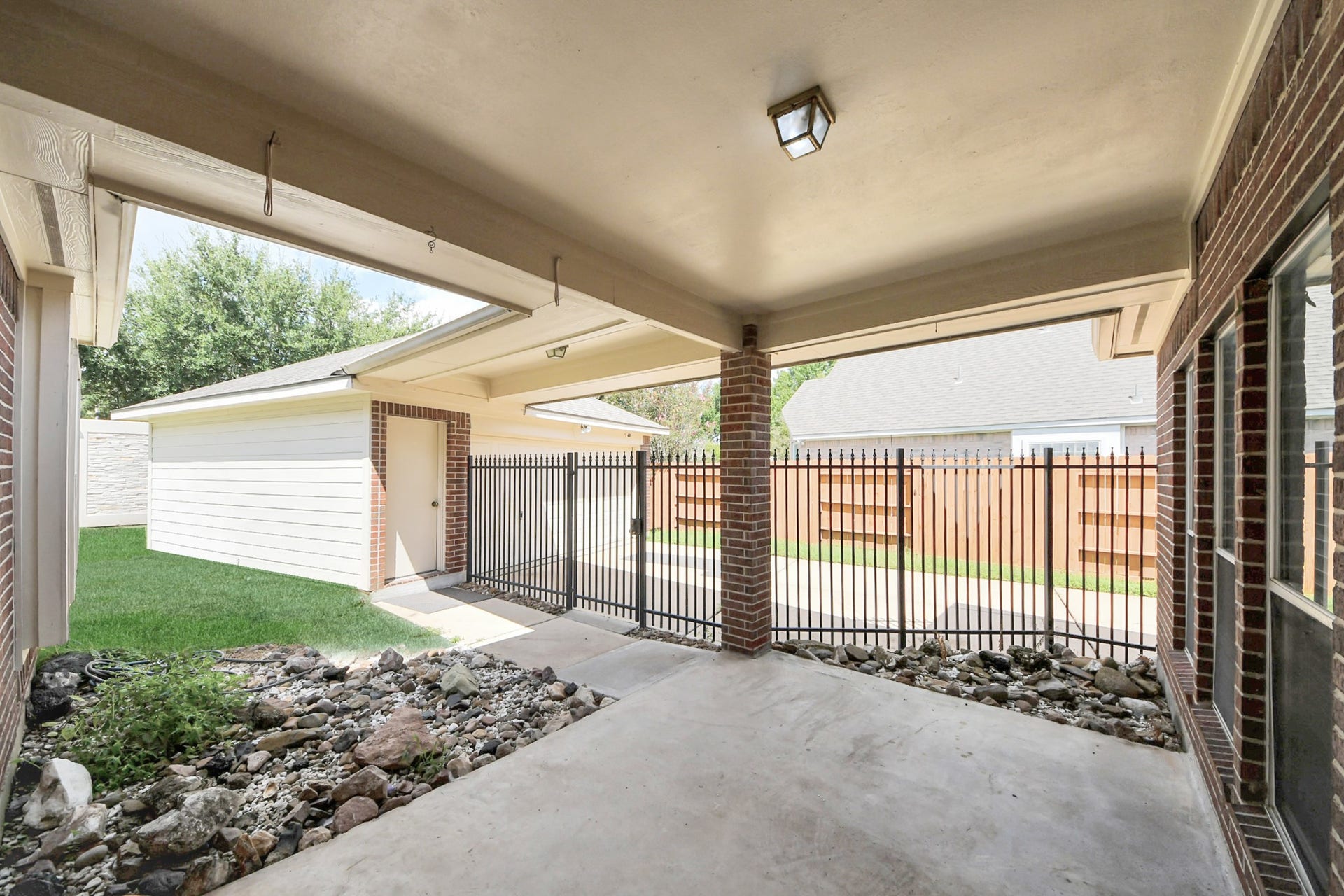 5815 Pheasant Ridge Lane, Houston, TX 77041 Spacious covered patio with brick accents, perfect for outdoor relaxation, overlooking a fenced yard with easy access to the garage.