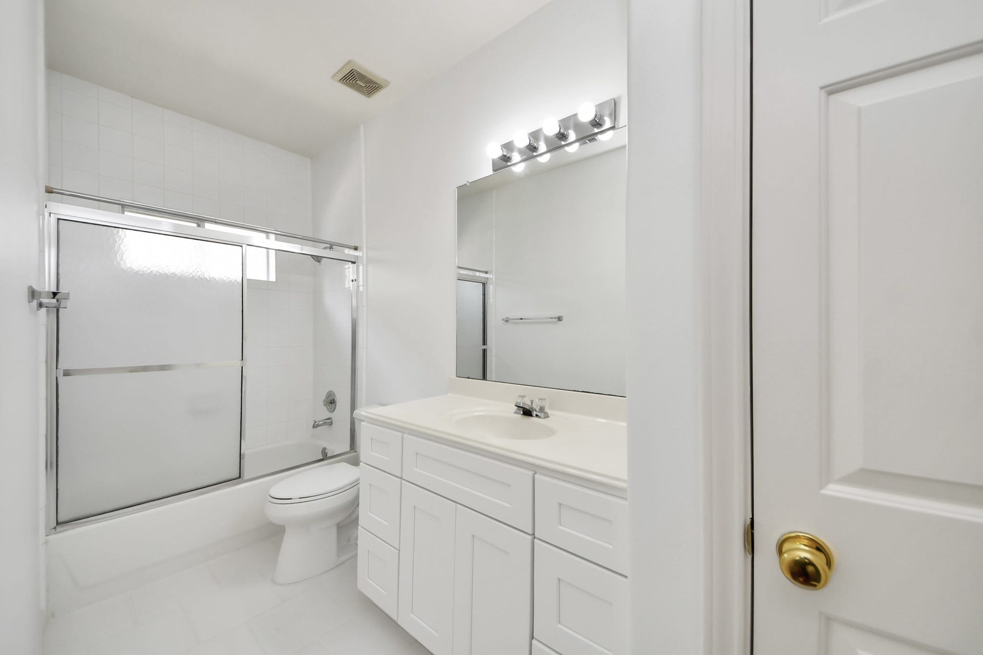 5815 Pheasant Ridge Lane, Houston, TX 77041 Bright and clean bathroom featuring a sleek white vanity, spacious mirror with modern lighting, and a shower-tub combo with sliding glass doors.