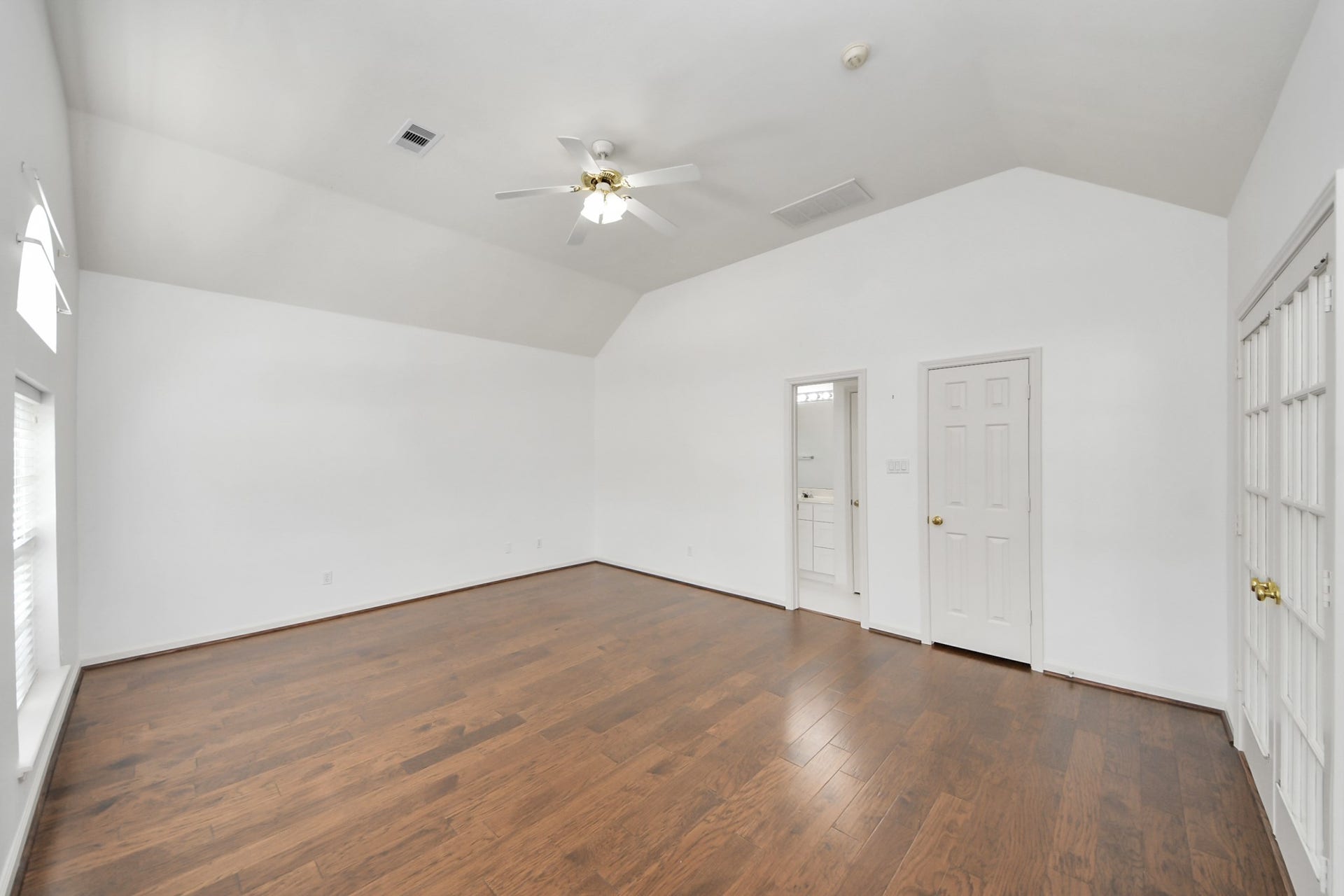 5815 Pheasant Ridge Lane, Houston, TX 77041 Spacious room with vaulted ceilings, elegant hardwood floors, and abundant natural light, featuring double French doors and convenient bathroom access.