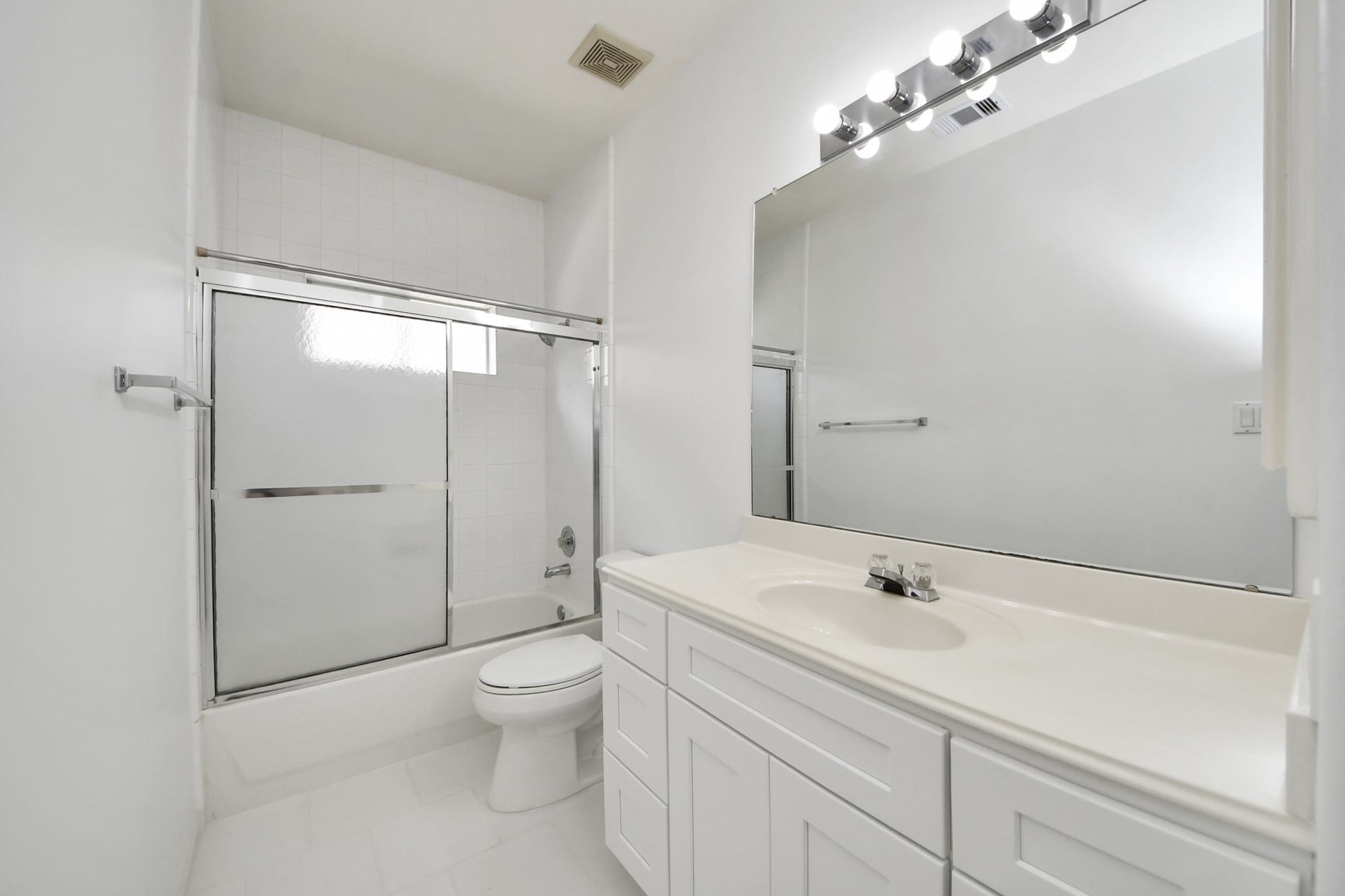 5815 Pheasant Ridge Lane, Houston, TX 77041 Bright and modern bathroom featuring a large mirror, sleek vanity with ample storage, and a glass-enclosed shower-tub combo.