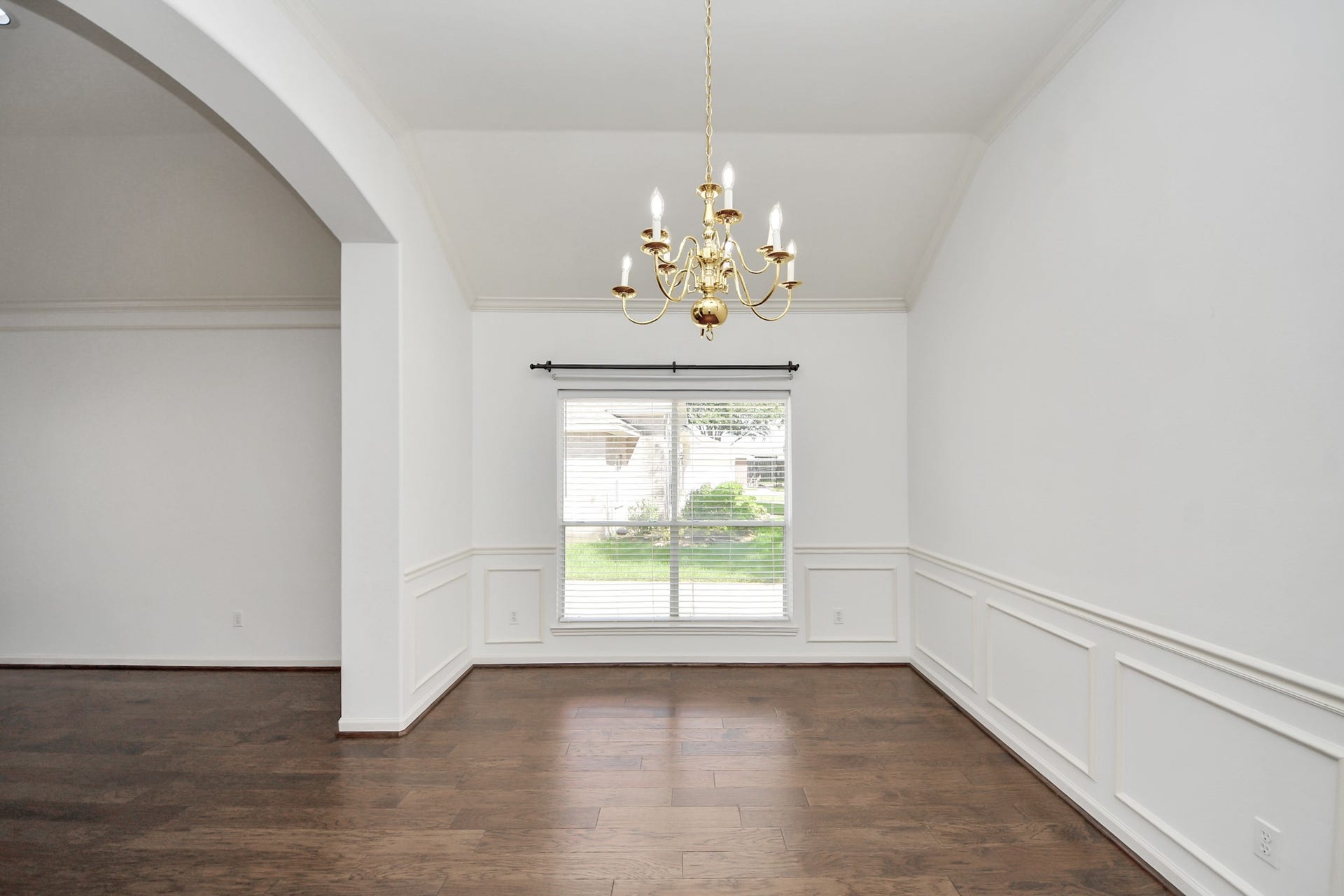 5815 Pheasant Ridge Lane, Houston, TX 77041 Elegant dining area with rich hardwood floors, a classic chandelier, and large window providing ample natural light.