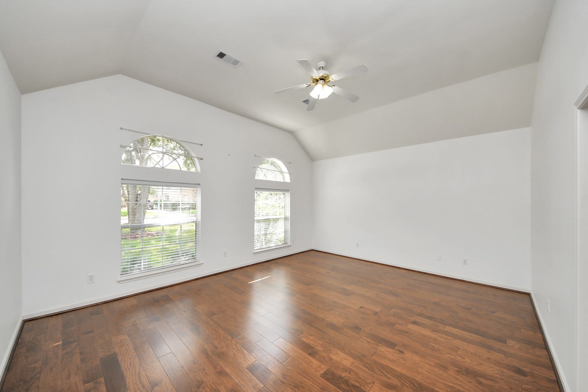 5815 Pheasant Ridge Lane, Houston, TX 77041 Spacious room with vaulted ceilings, rich hardwood floors, and abundant natural light from elegant arched windows.