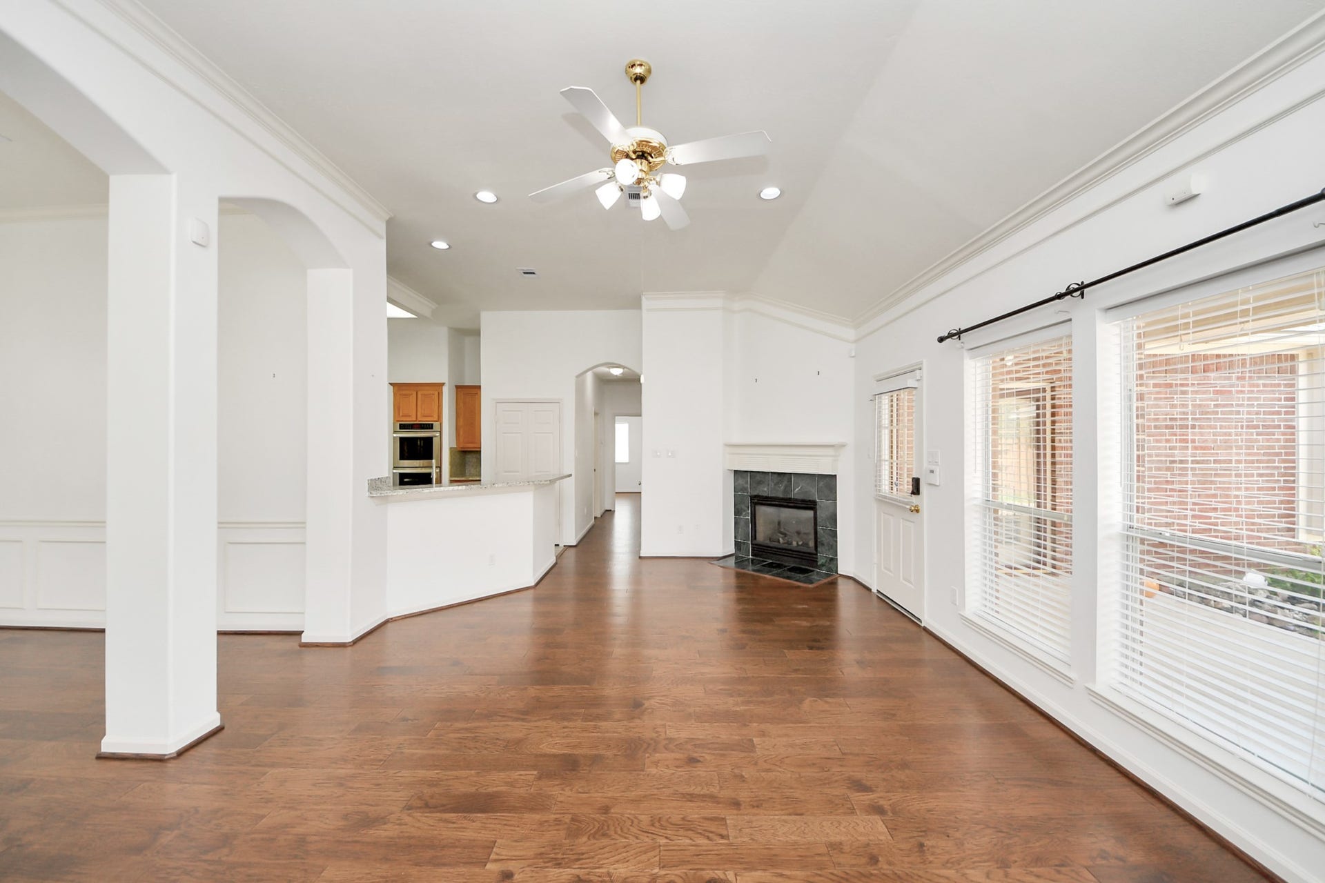 5815 Pheasant Ridge Lane, Houston, TX 77041 Spacious bedroom area featuring elegant hardwood floors, a cozy fireplace, and abundant natural light through large windows, seamlessly connecting to a modern kitchen with an inviting breakfast bar.