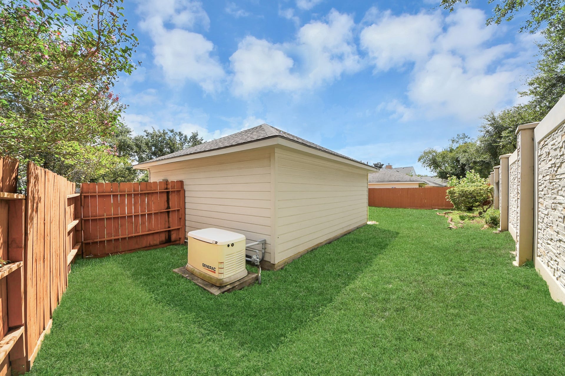 5815 Pheasant Ridge Lane, Houston, TX 77041 Spacious backyard featuring lush green grass, a sturdy wooden fence for privacy, and a convenient storage shed.