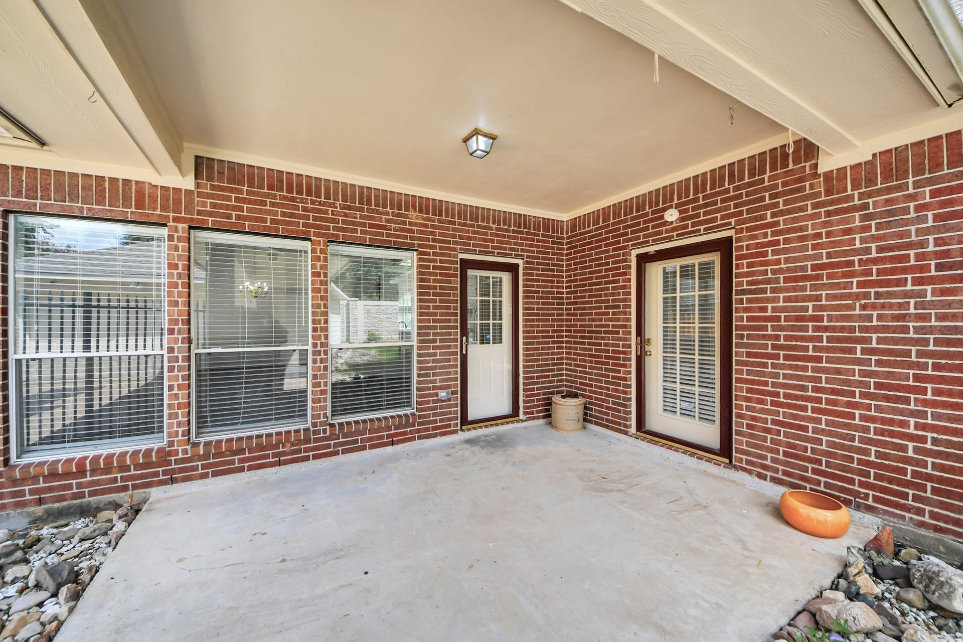 5815 Pheasant Ridge Lane, Houston, TX 77041 Charming brick patio with ample natural light, featuring dual French doors and large windows, perfect for relaxing or entertaining.