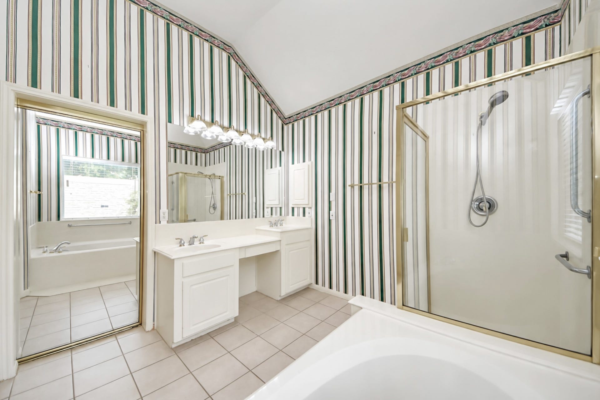 5815 Pheasant Ridge Lane, Houston, TX 77041 Spacious bathroom featuring a dual vanity, separate shower, and a relaxing bathtub, all accented by classic striped wallpaper and ample natural light.