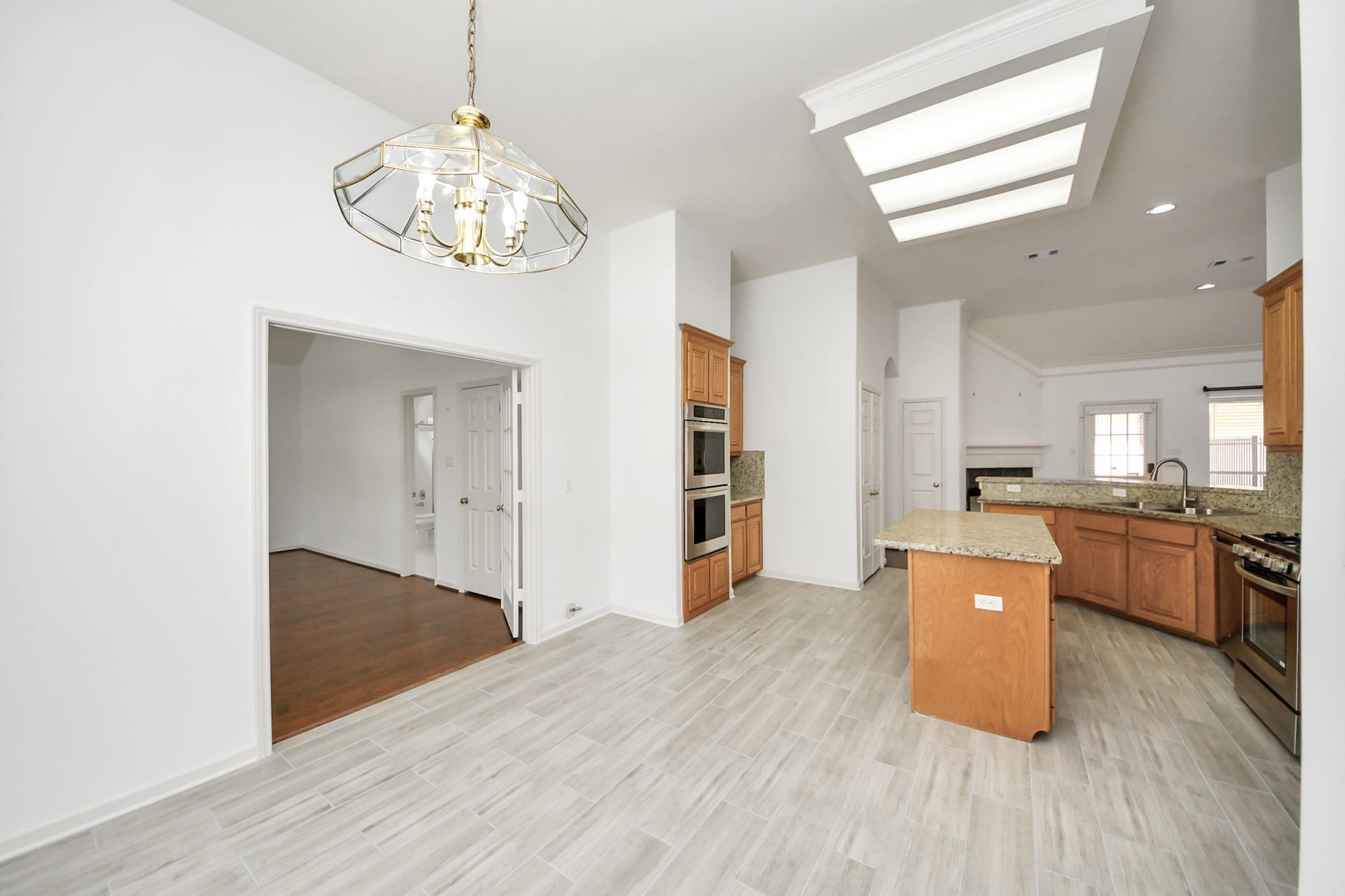 5815 Pheasant Ridge Lane, Houston, TX 77041 Spacious kitchen with granite countertops, modern appliances, and ample cabinetry, flowing seamlessly into a bright dining area under a stylish chandelier.