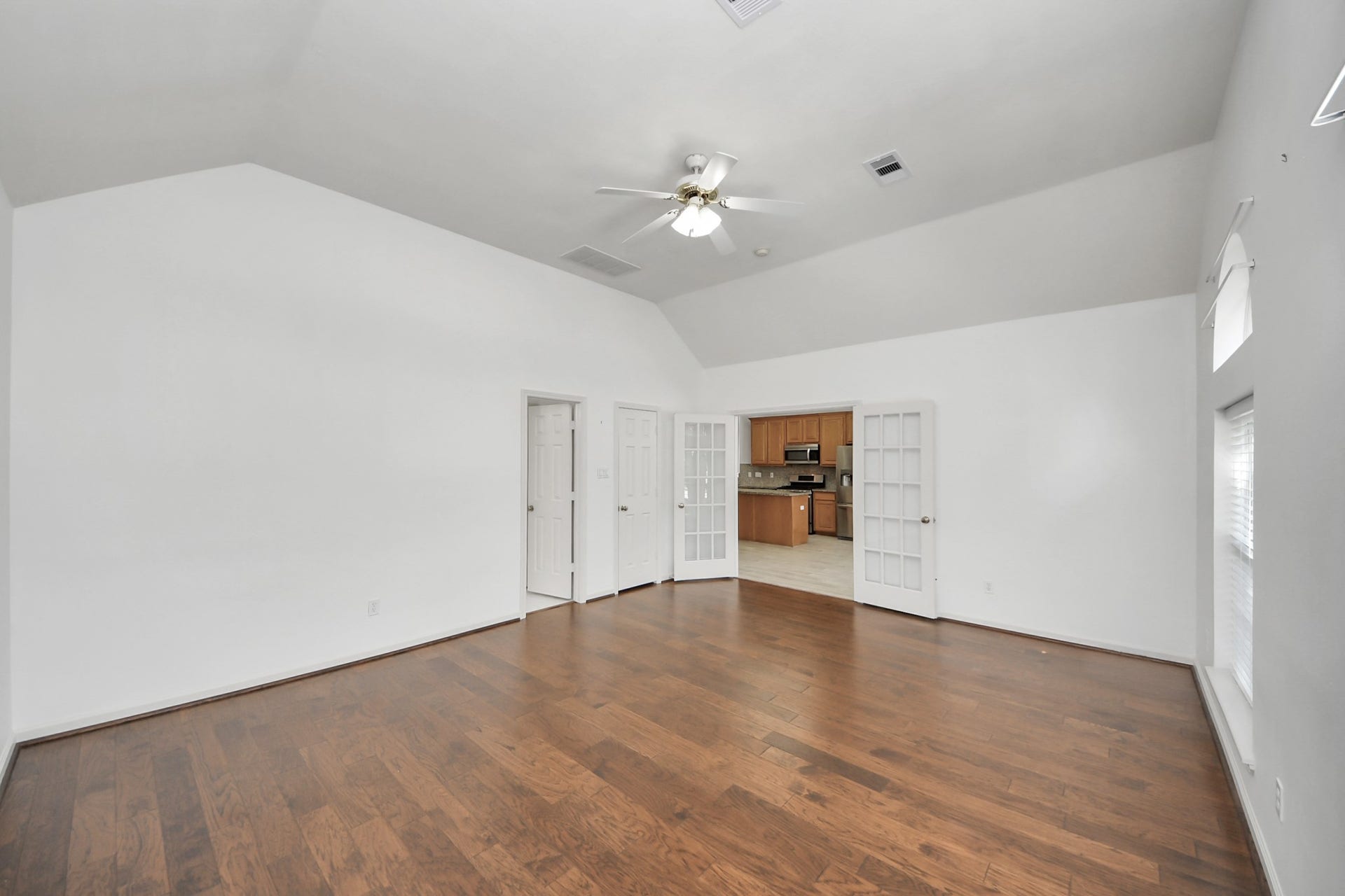 5815 Pheasant Ridge Lane, Houston, TX 77041 Spacious living area featuring elegant hardwood floors and high ceilings, with French doors opening to a modern kitchen.