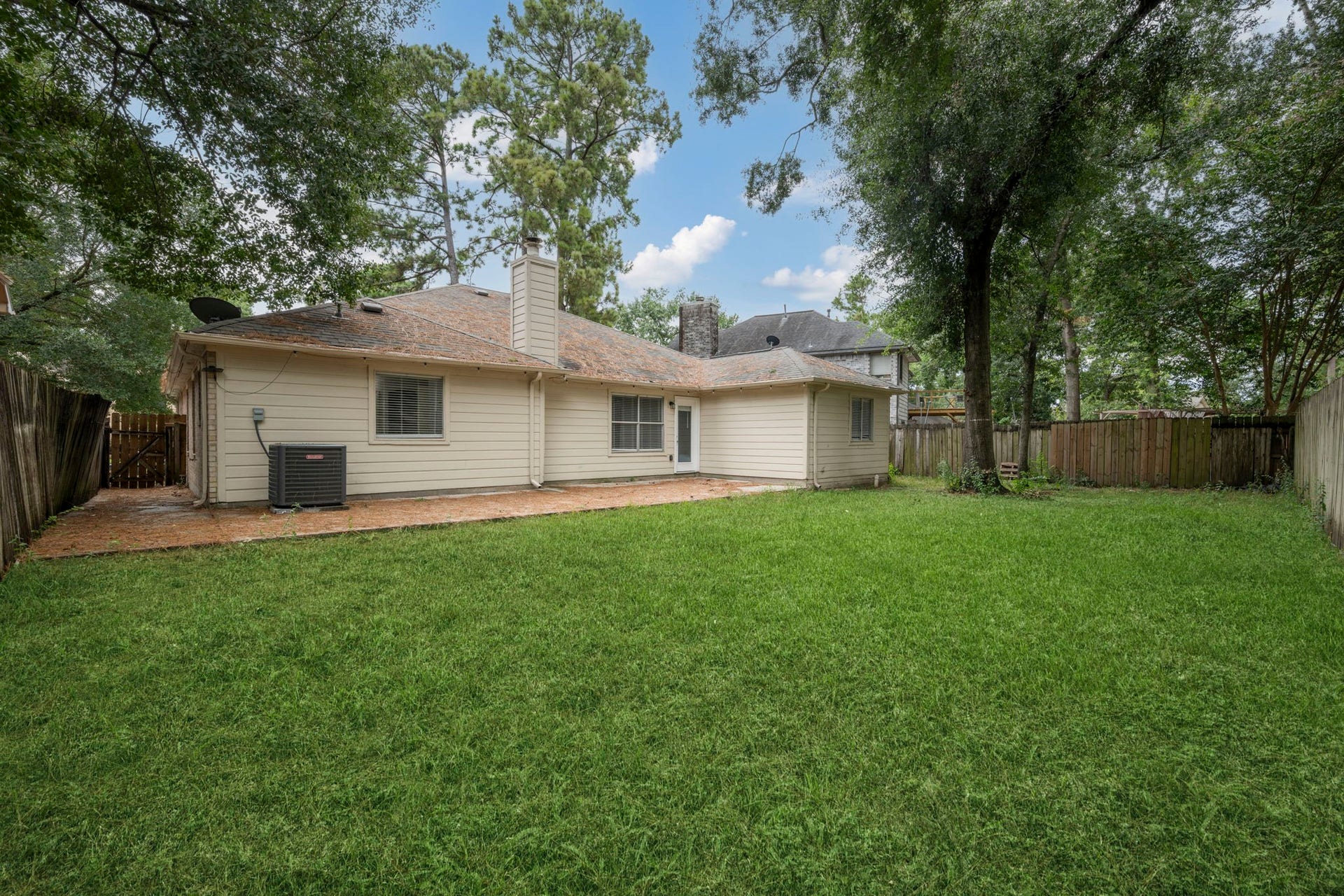Spacious backyard with lush grass and a charming patio area, perfect for outdoor gatherings and relaxation.