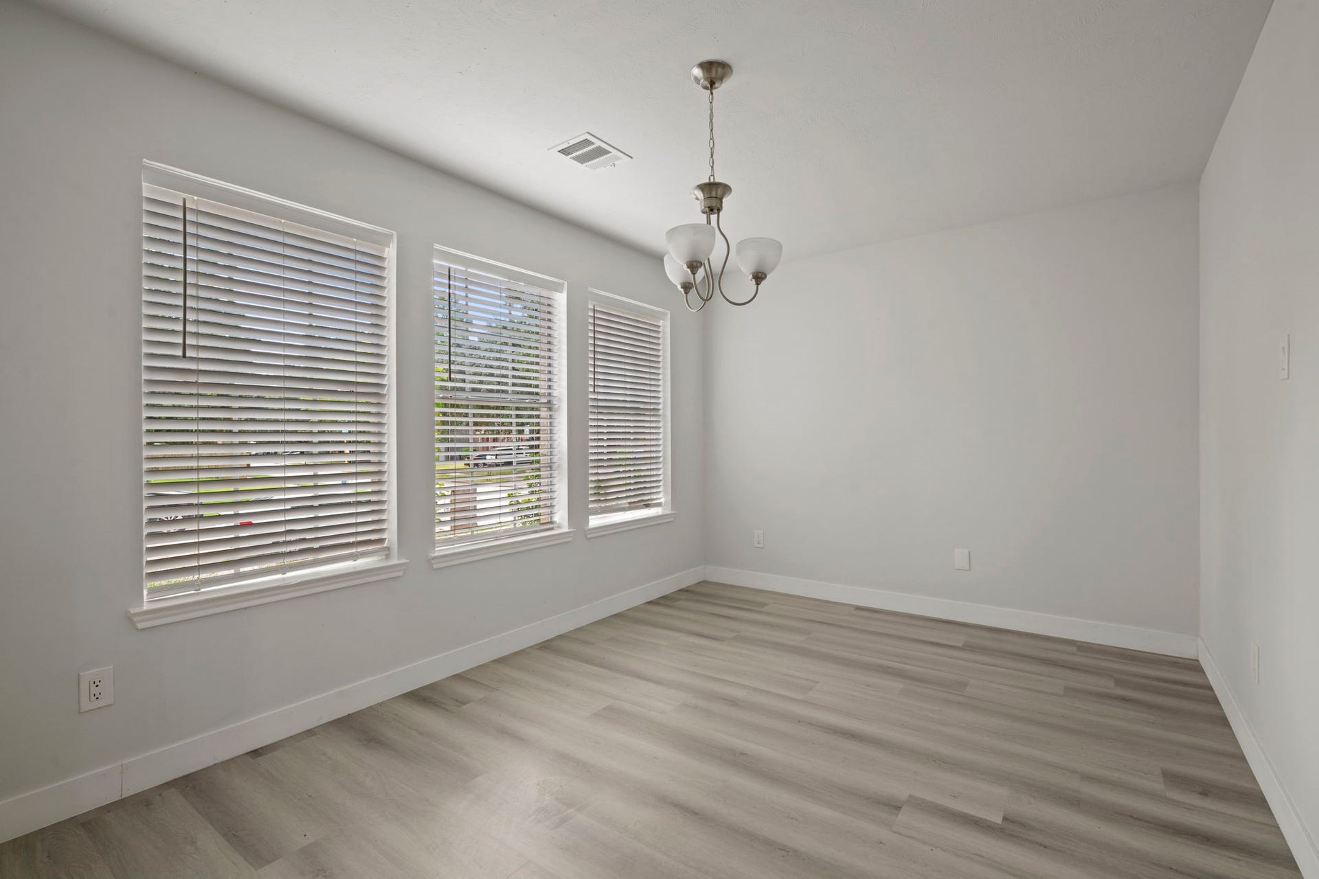 Bright dining area with large windows, modern light fixture, and sleek wood flooring. (Formal Dinning(