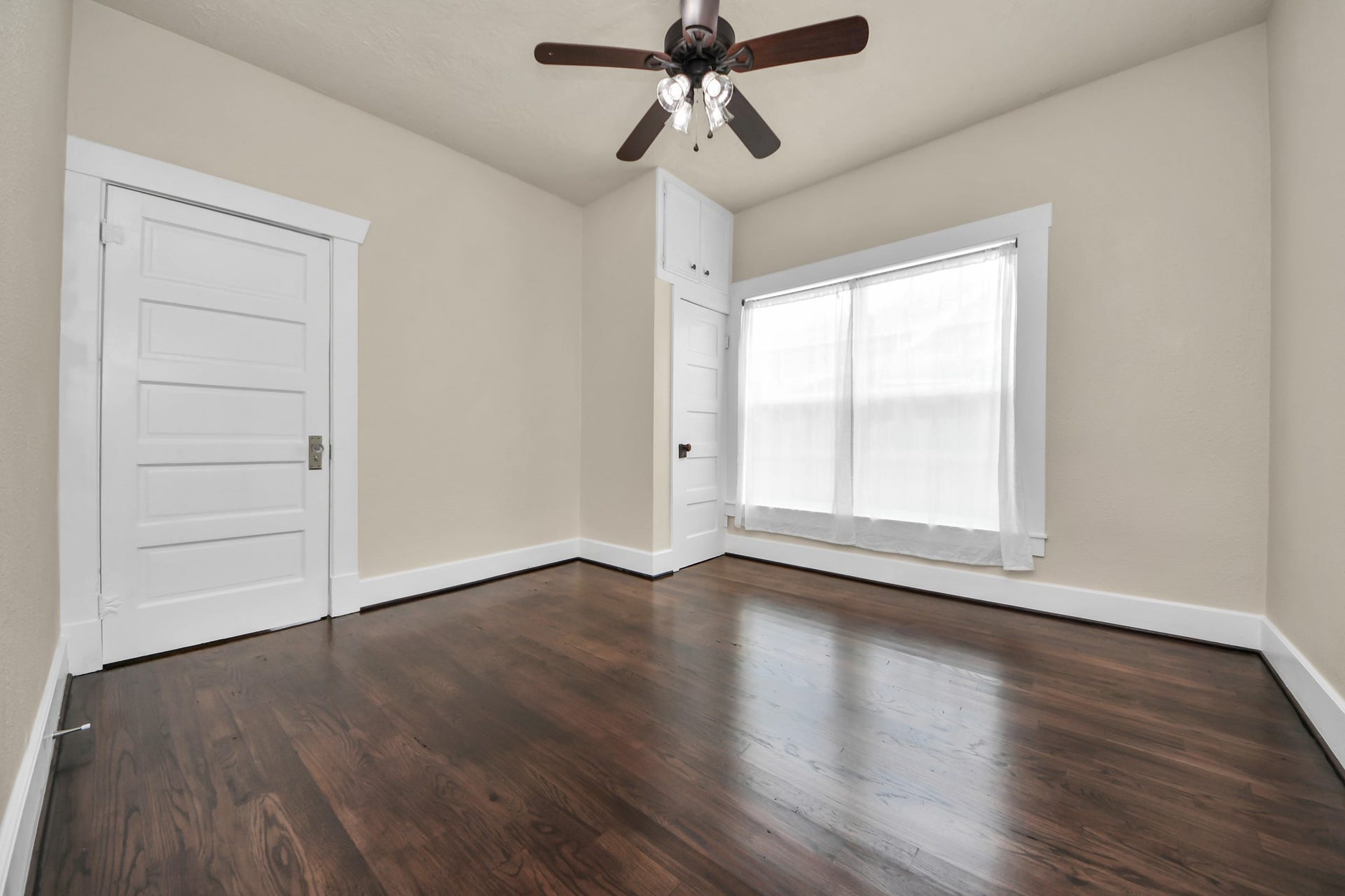 A generously sized secondary bedroom showcasing original hardwood floors and beautiful natural light.