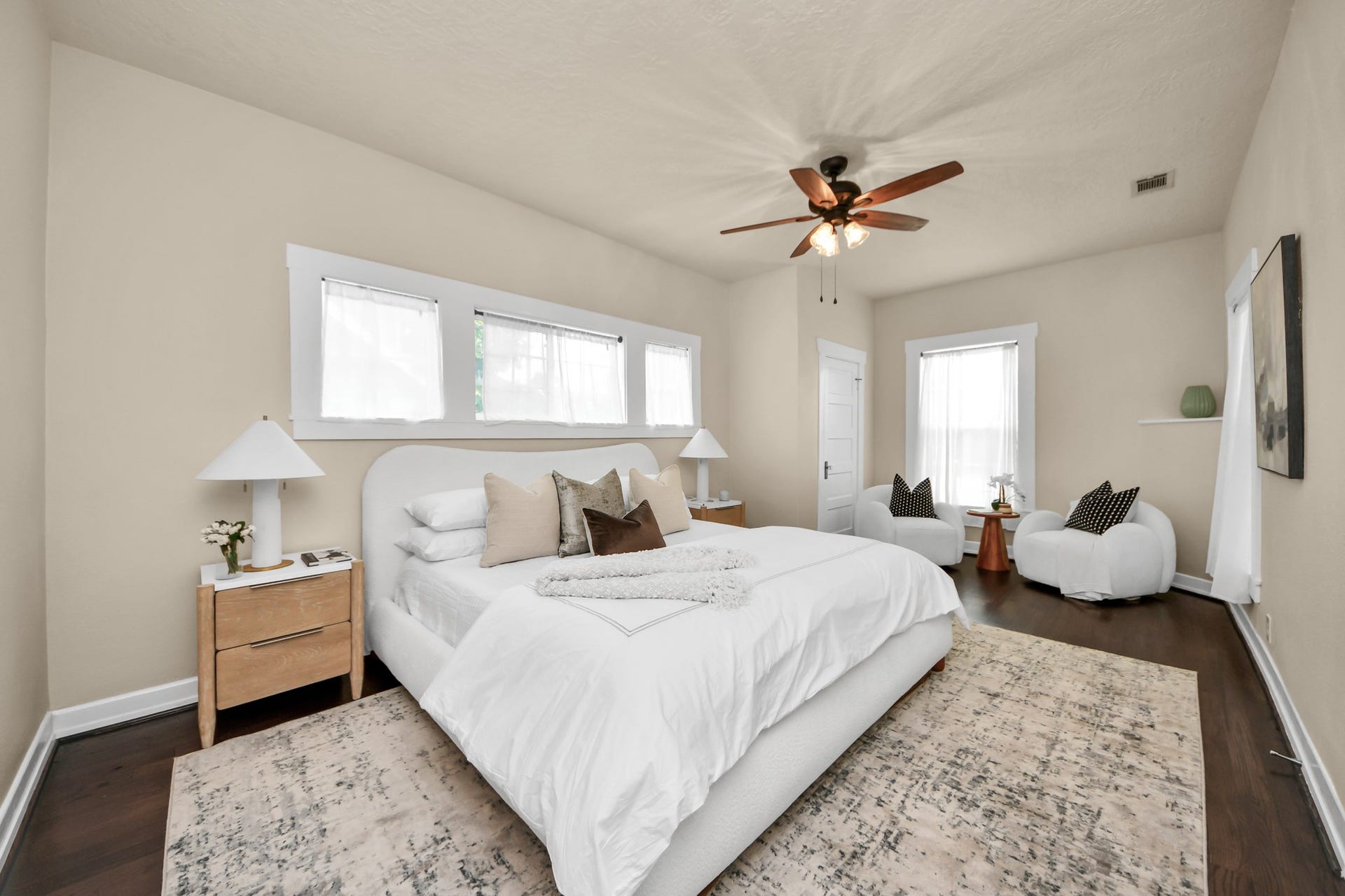 This spacious bedroom offers a serene retreat with hardwood flooring and abundant natural light.
